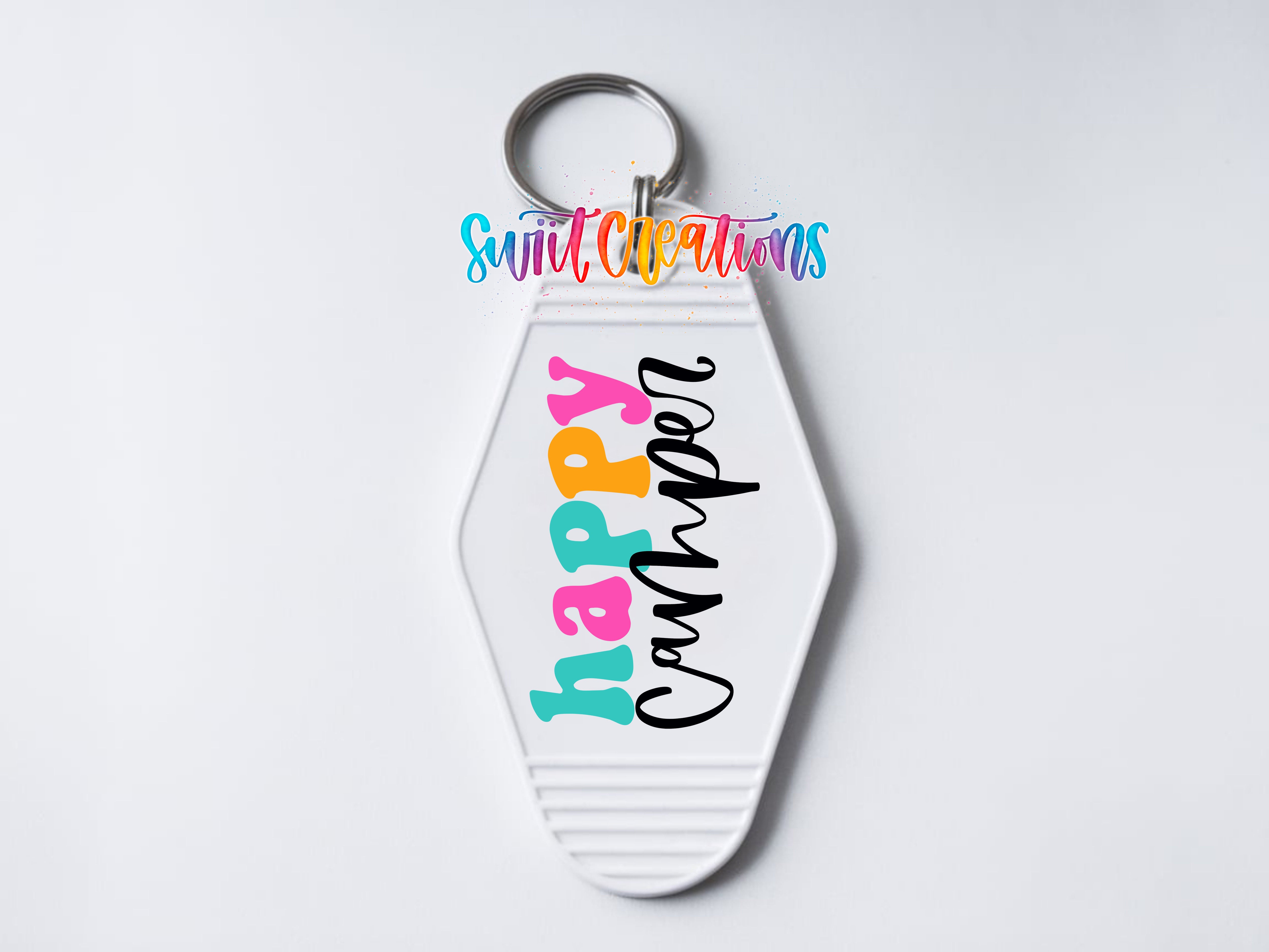 A keychain with the text "Happy Camper" printed on it, along with a colorful design.