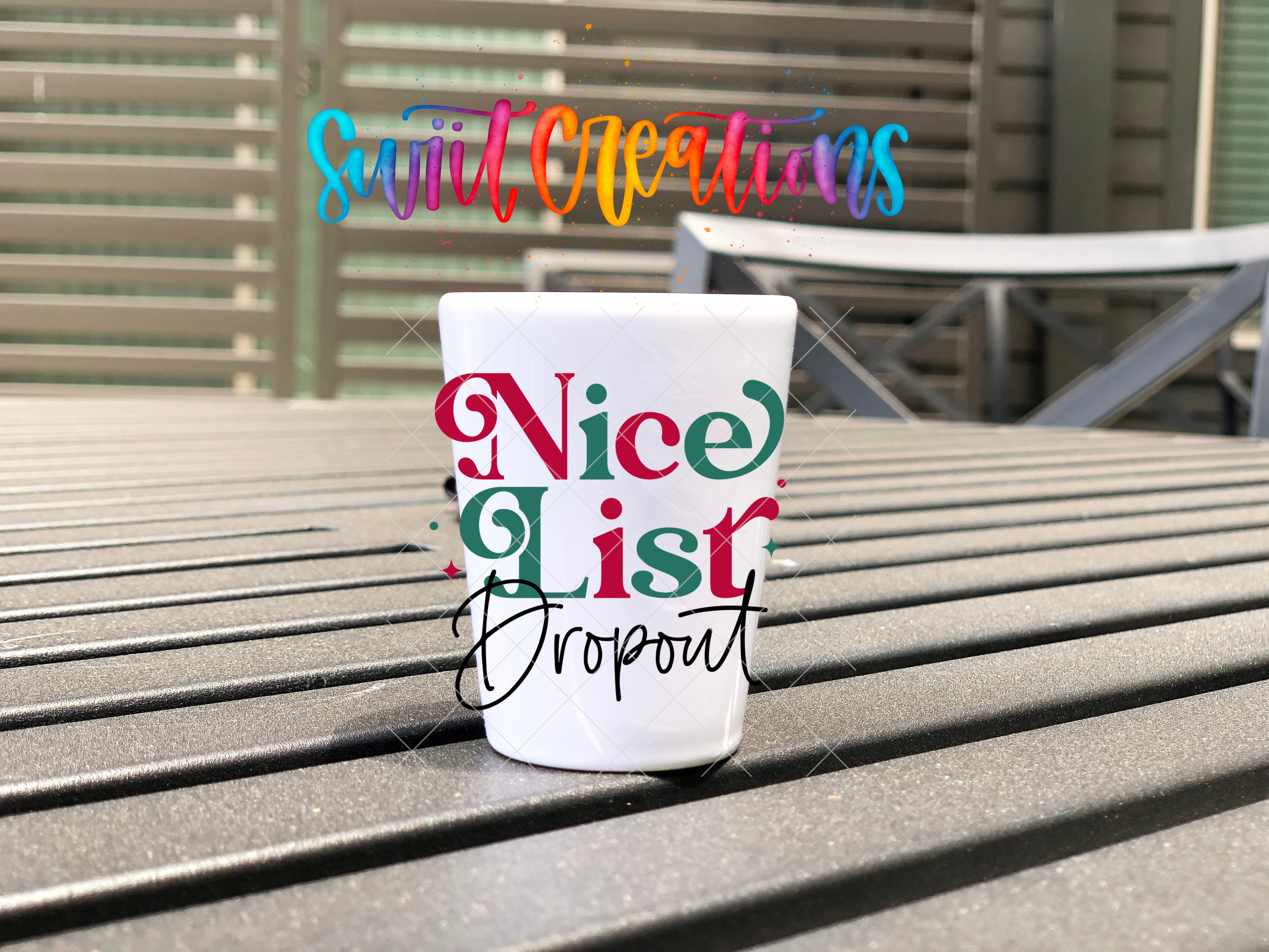 A white mug with the text " Nice List Dropout" printed on it, placed on a wooden surface.