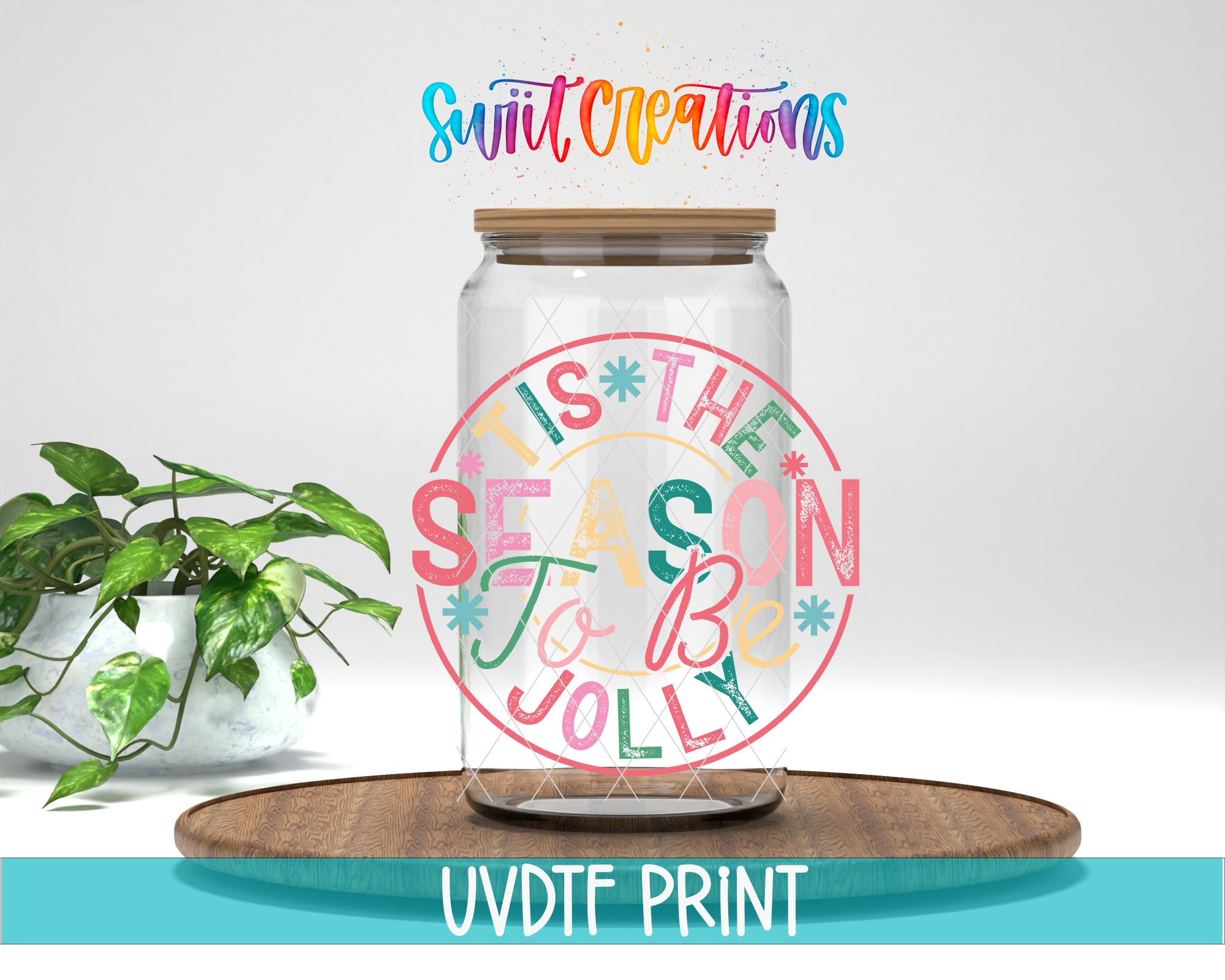 A glass jar with a lid, featuring a colorful and festive design, placed on a wooden surface next to a potted plant.