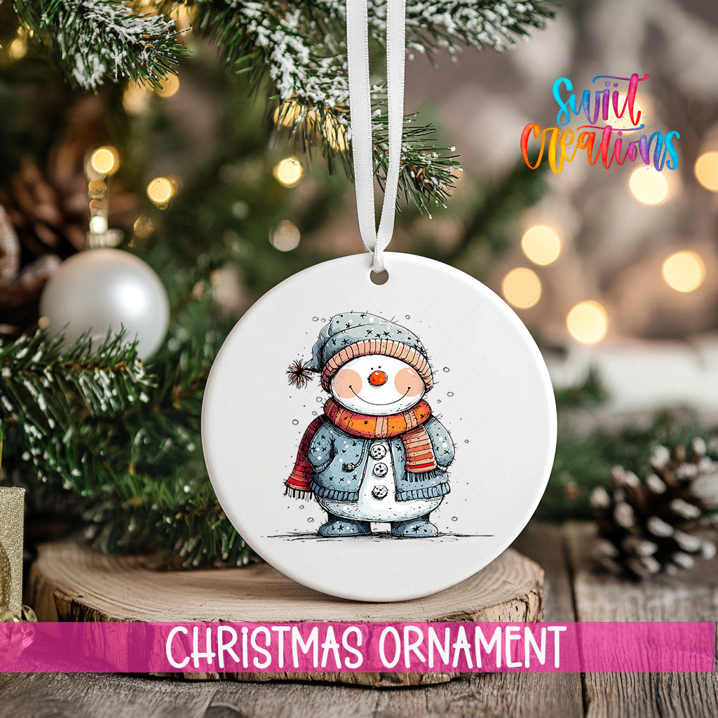 A white Christmas ornament featuring a smiling snowman is hanging from a string, surrounded by a decorated Christmas tree and pine cones.