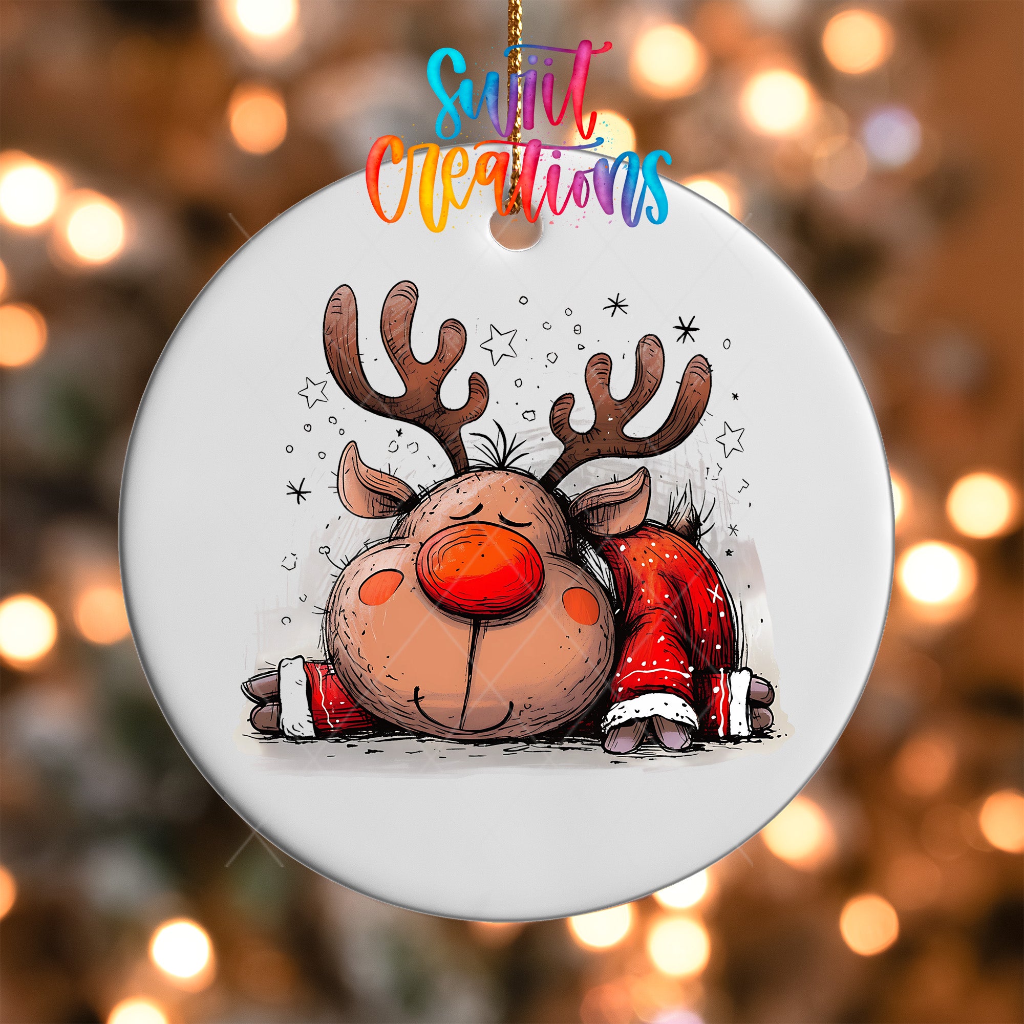 A white ornament featuring a cartoon reindeer with antlers and a red nose, surrounded by stars and snowflakes, against a blurred background of lights.