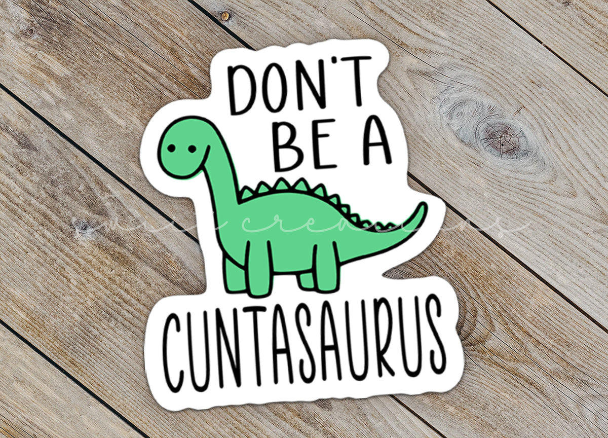 Close-up of the Don't Be a C*ntasaurus sticker on rustic wood