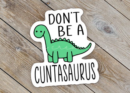 Close-up of the Don't Be a C*ntasaurus sticker on rustic wood
