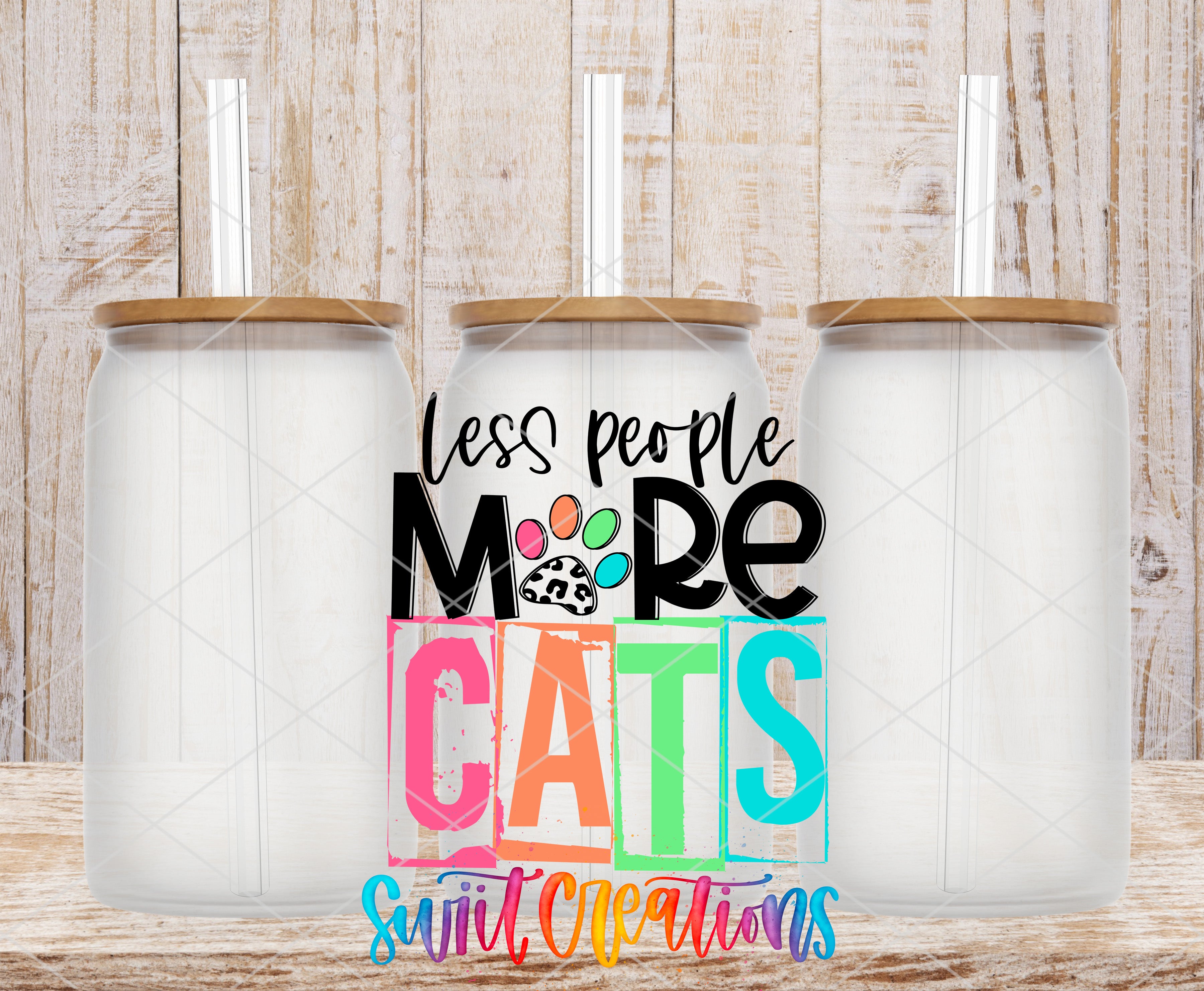 three clear glass jars with lids, arranged in a row against a wooden background. The jars have straws sticking out of the lids. The text "less people, more cats" is displayed in a colorful, stylized font, and the phrase "Sweet Creations" is written below the text.