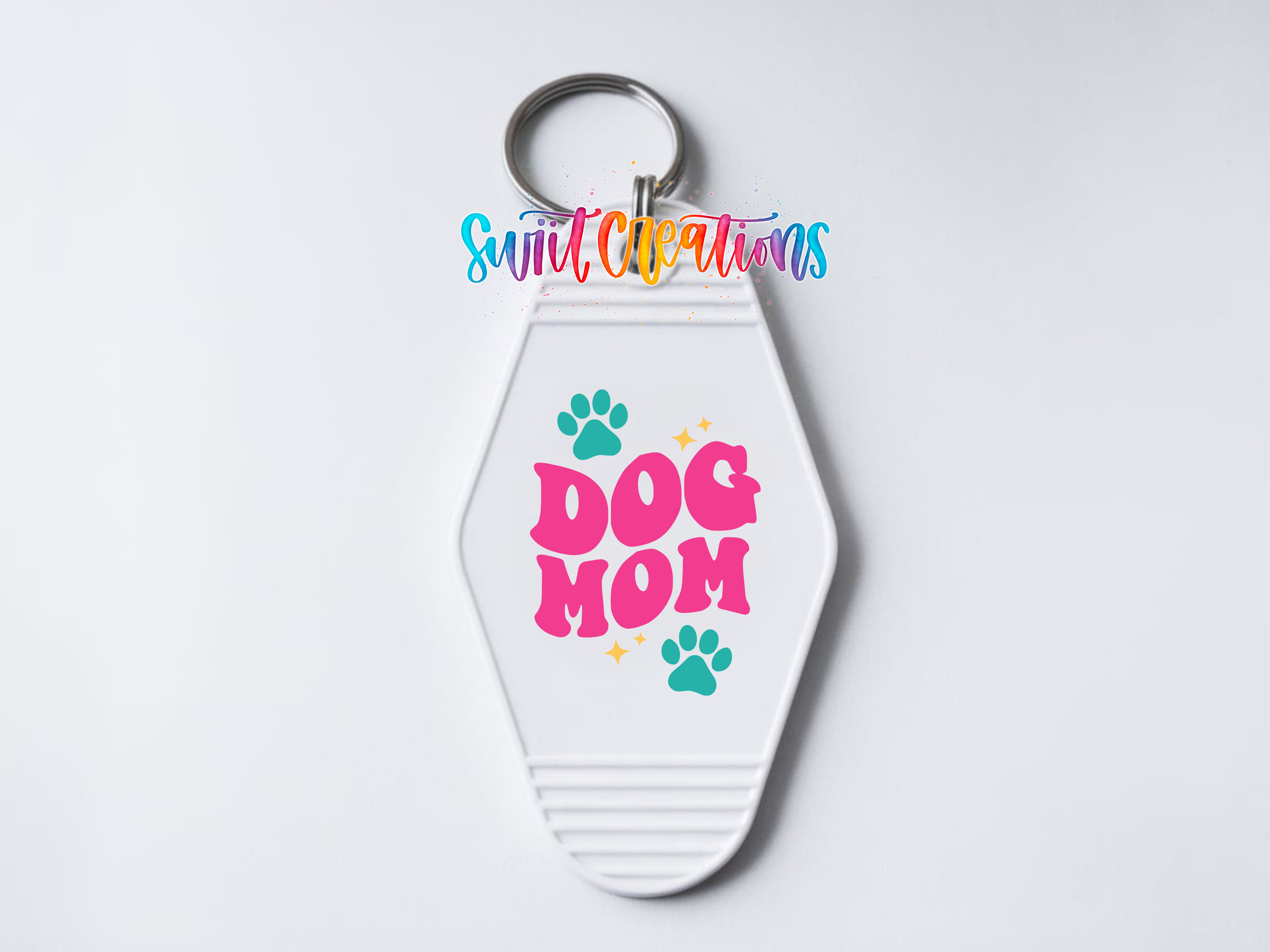 A white keychain with a keyring and the text "DOG MOM" printed on it.