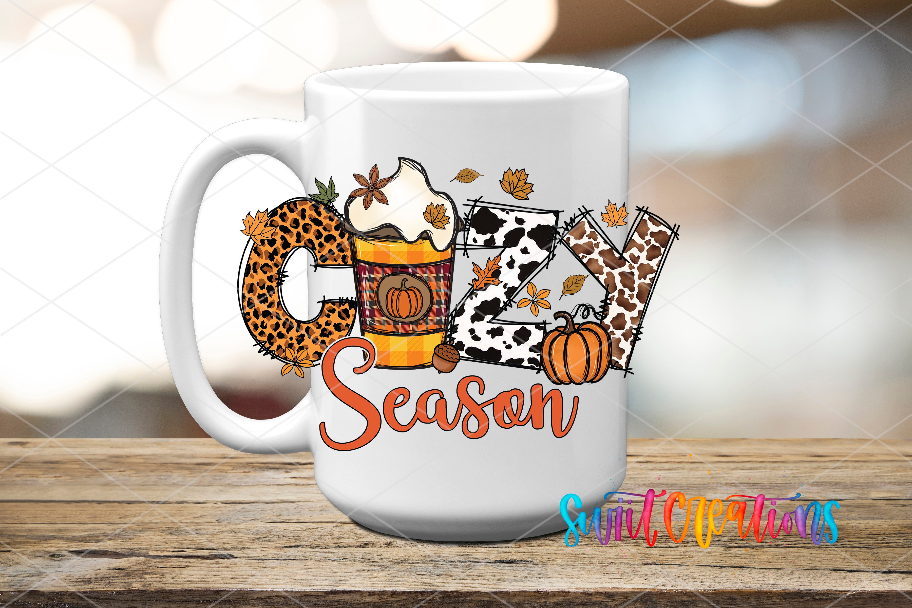 A white mug with a colorful design featuring the word "Cozy" surrounded by autumn-themed elements such as leaves, pumpkins, and a leopard print.