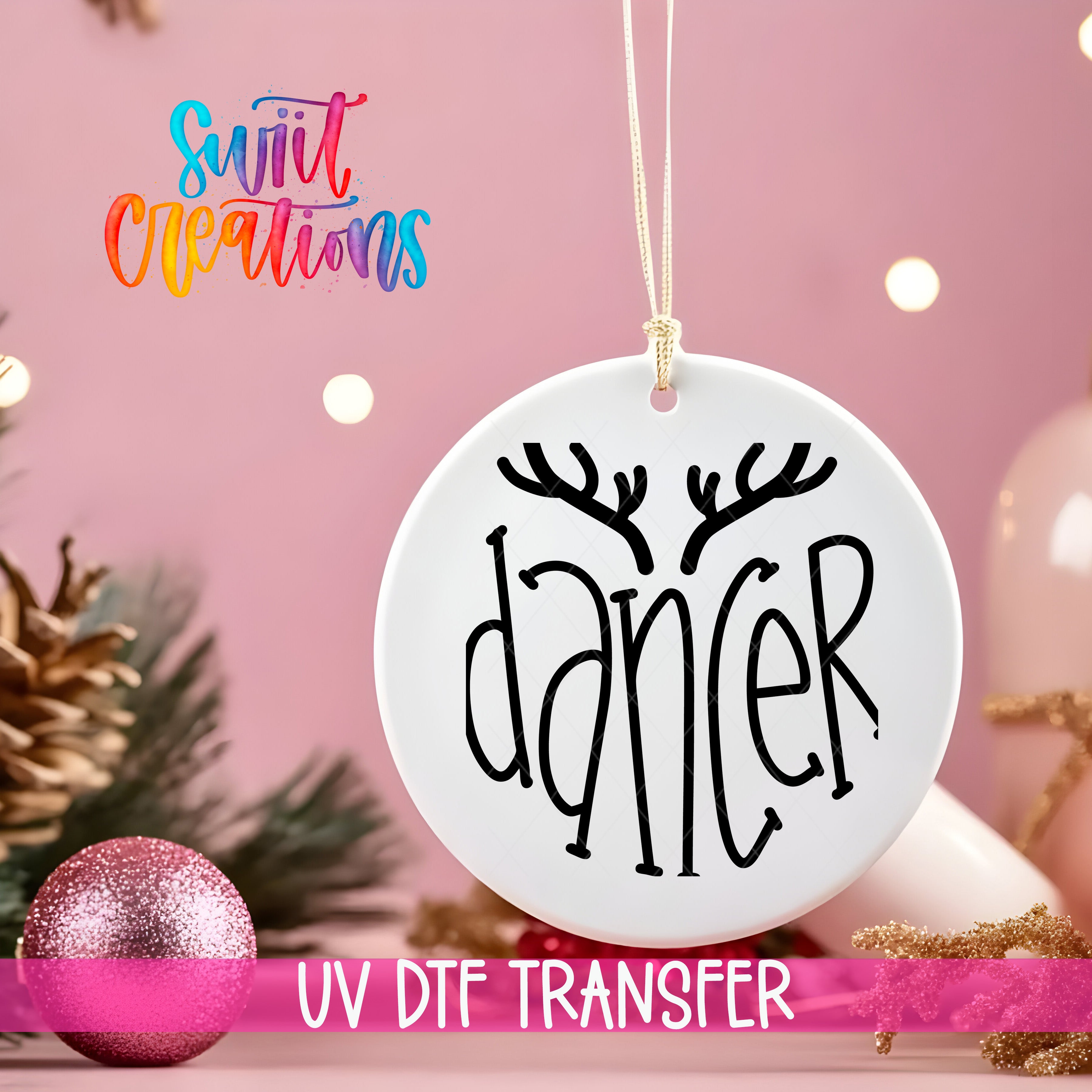 A white ornament with the word "dancer" written on it, hanging on a string against a pink background with Christmas decorations in the background.