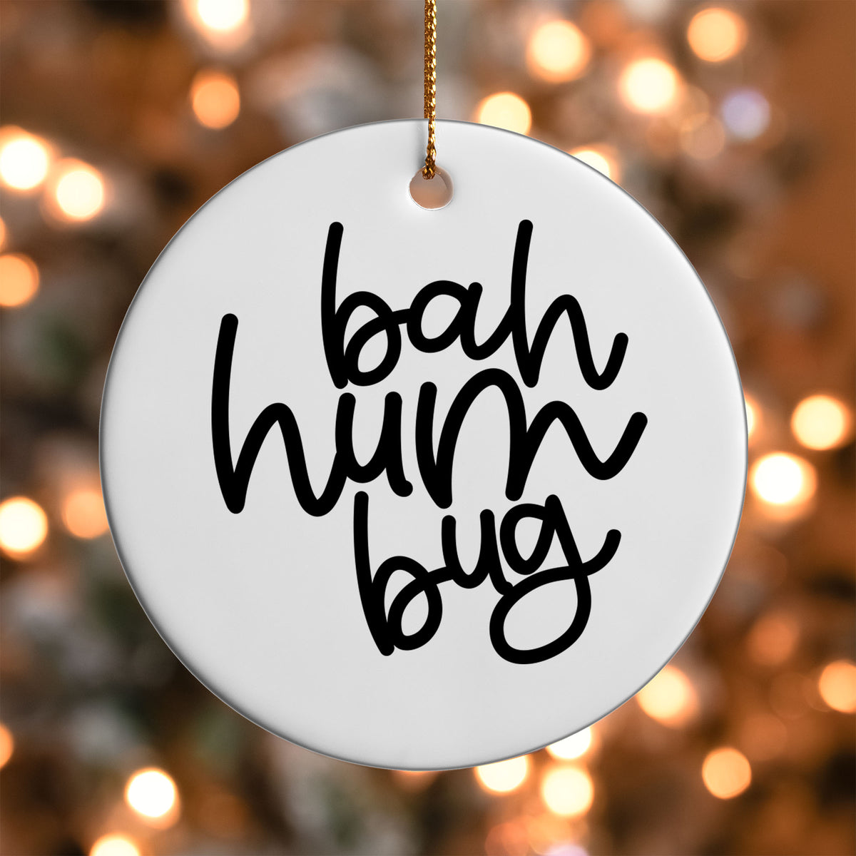 Bah Humbug ornament UV DTF transfer on a round white ornament with a bokeh light background