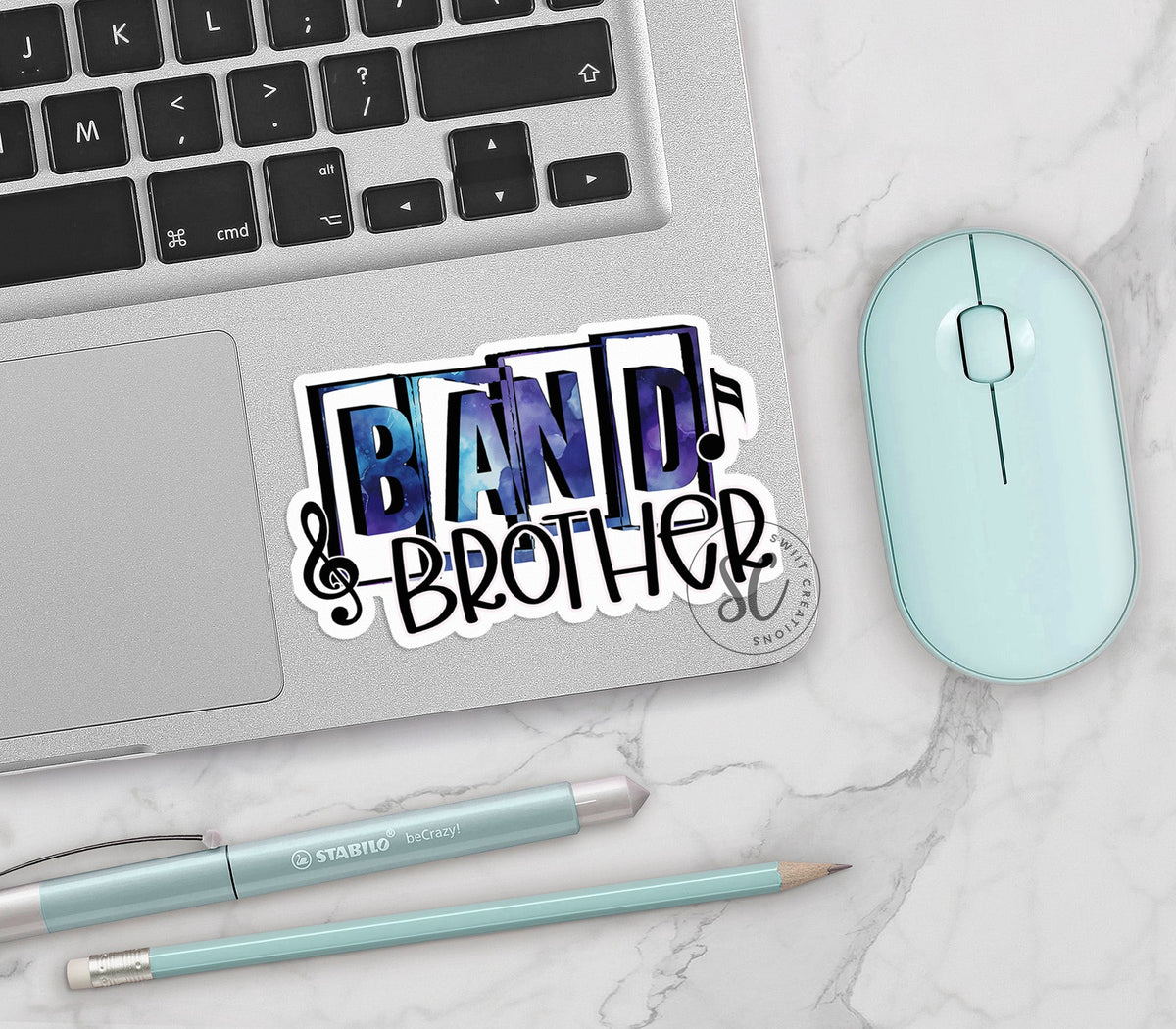 Blue Band Brother vinyl sticker on a silver laptop next to a mint mouse and pens