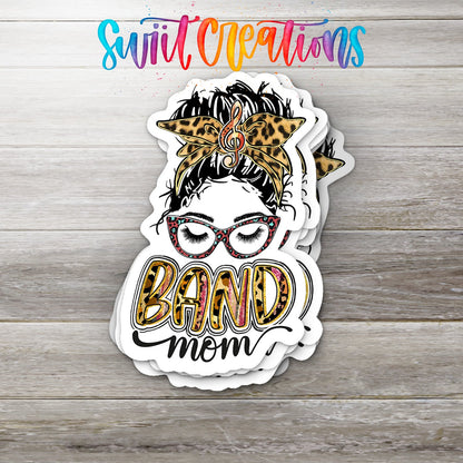 Stack of Leopard Messy Bun Band Mom glossy stickers on a gray wood table