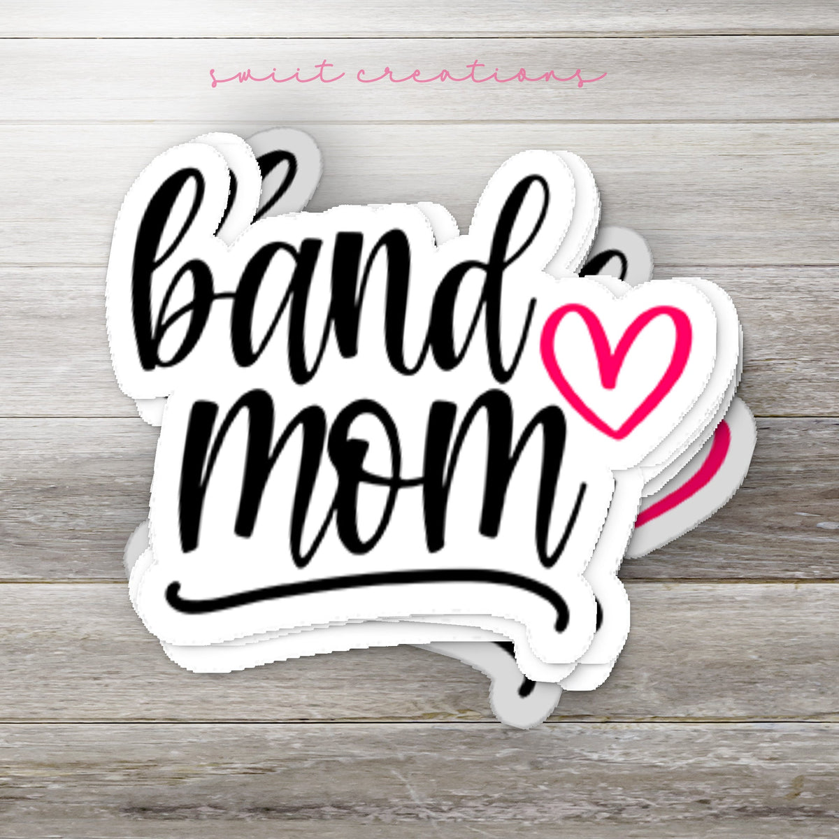 Stack of Pink Heart Band Mom glossy stickers on a gray wood table