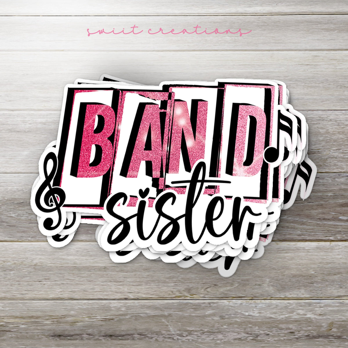 Stack of Pink Band Sister glossy stickers on a gray wood table
