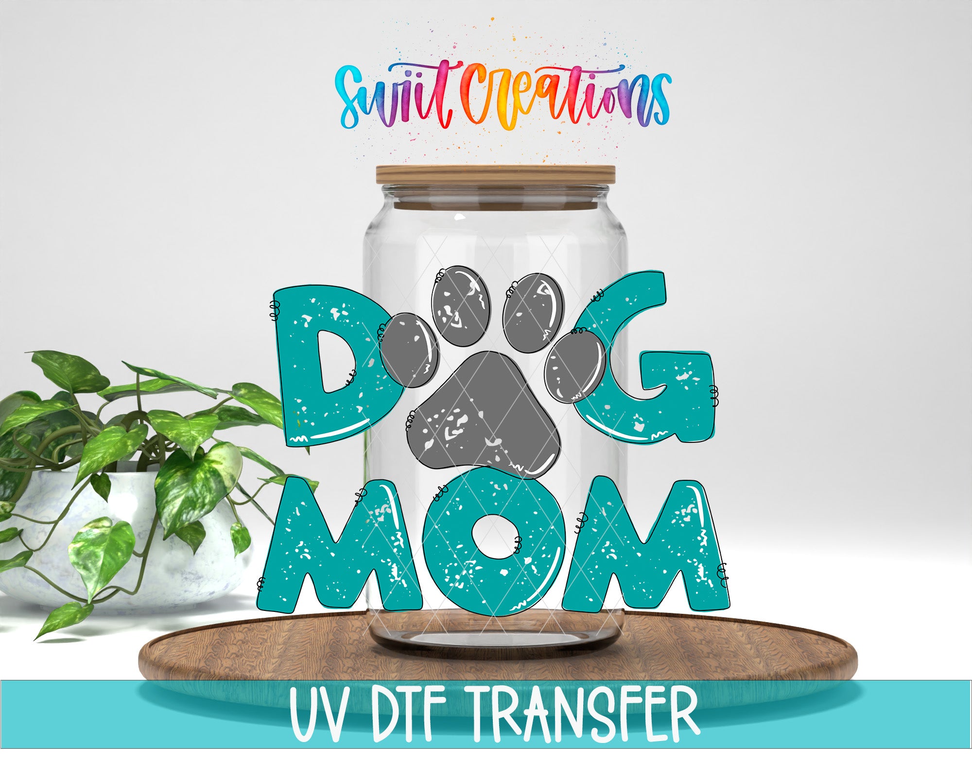 a glass jar with a dog paw print design, surrounded by the text "DOG MOM" in a stylized font. The jar is placed on a wooden surface, and there is a potted plant in the background.