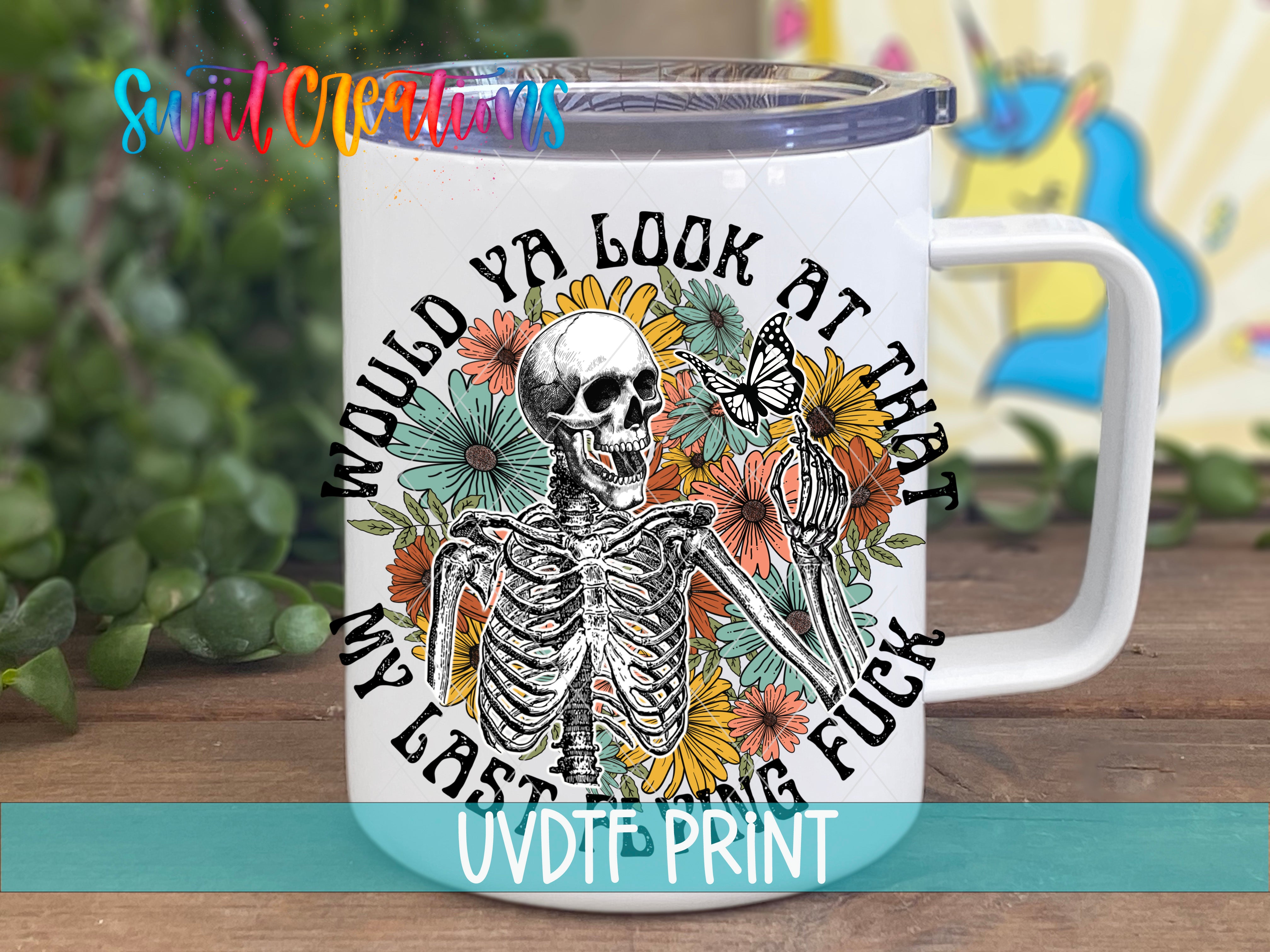 A white ceramic mug with a colorful graphic design featuring a skeleton, flowers, and a butterfly.