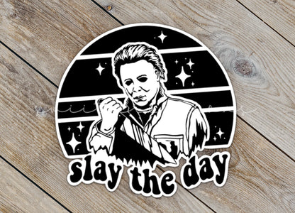 Close-up of the Slay the Day sticker on rustic wood