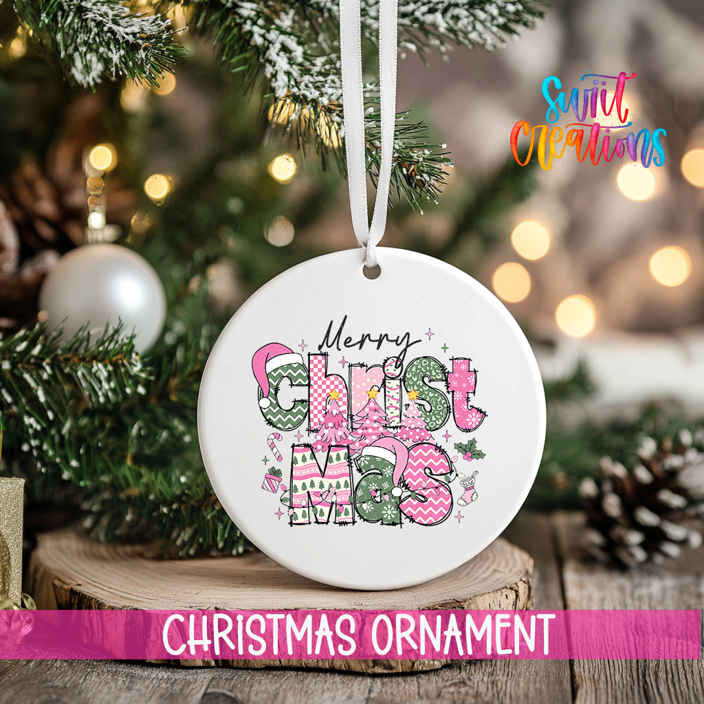 A white Christmas ornament with the text "Merry Christmas" in pink and green colors, hanging on a tree branch.