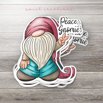 Stack of Peace Gnomie glossy stickers on a gray wood table