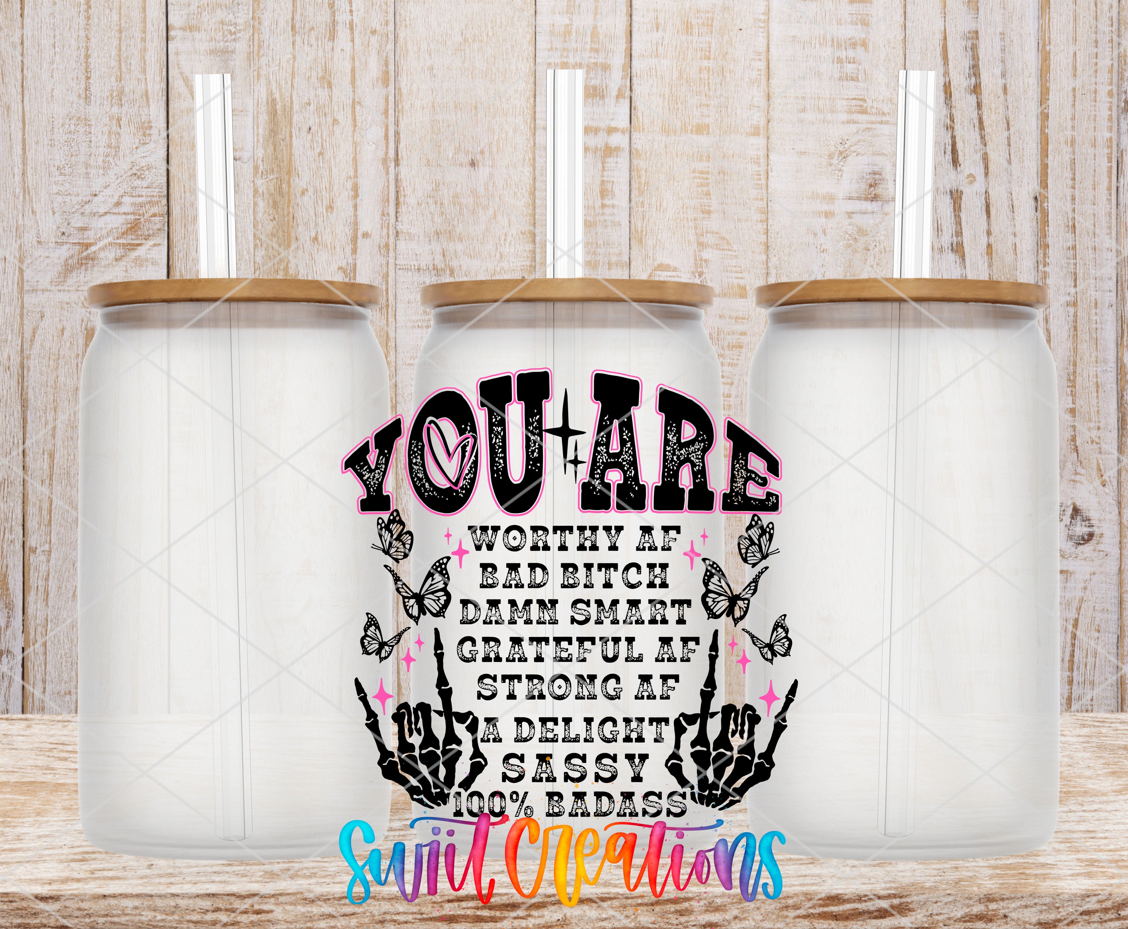 three glass jars with lids, arranged in a row against a wooden background. The jars have a unique design with a text overlay that reads "YOU ARE WORTHY OF A BAD BITCH DADDY SMART GRATEFUL OF STRONG AF A DELIGHT SASSY 100% BADASS".