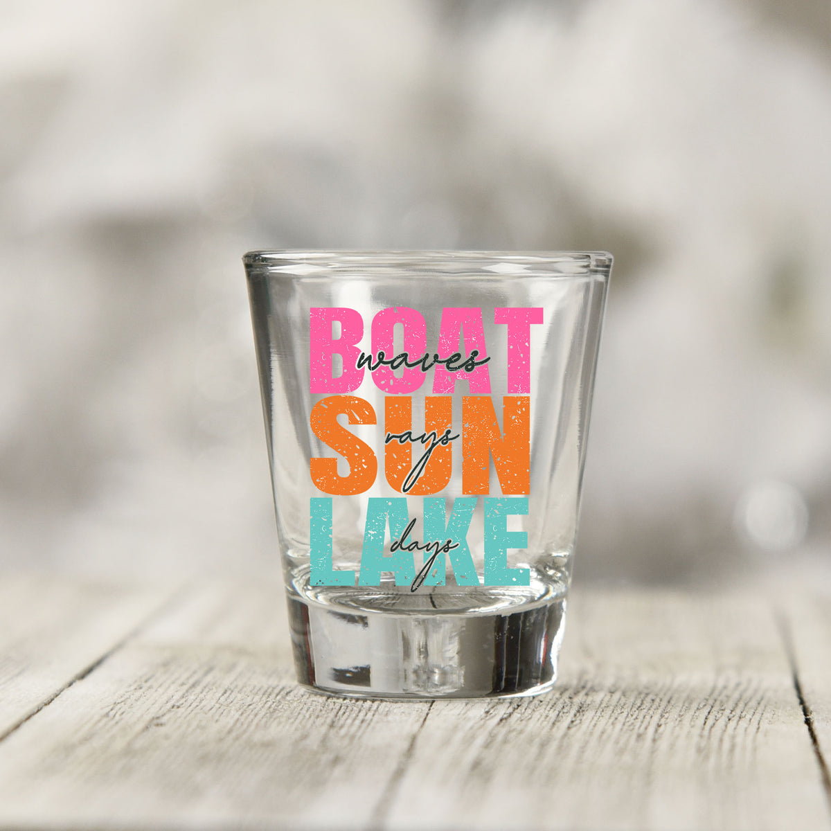 Close-up of the Boat Waves Sun Rays Lake Days UV DTF transfer on a clear shot glass
