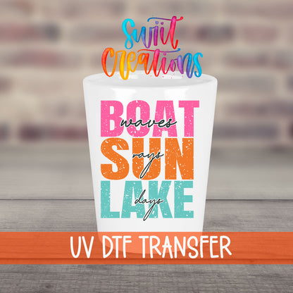 Boat Waves Sun Rays Lake Days UV DTF transfer on a white shot glass in front of a brick wall