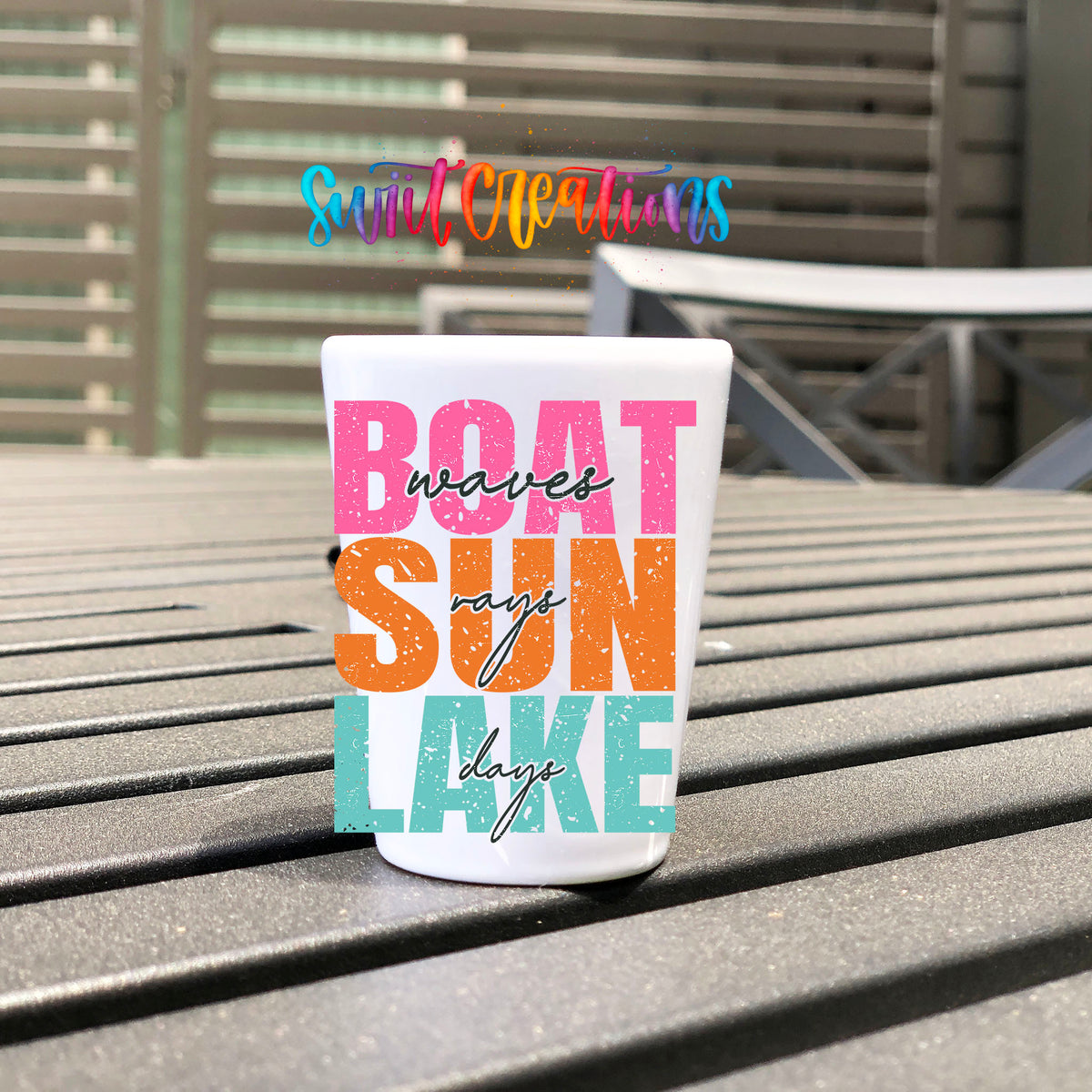 Boat Waves Sun Rays Lake Days UV DTF transfer on a white shot glass on an outdoor patio table