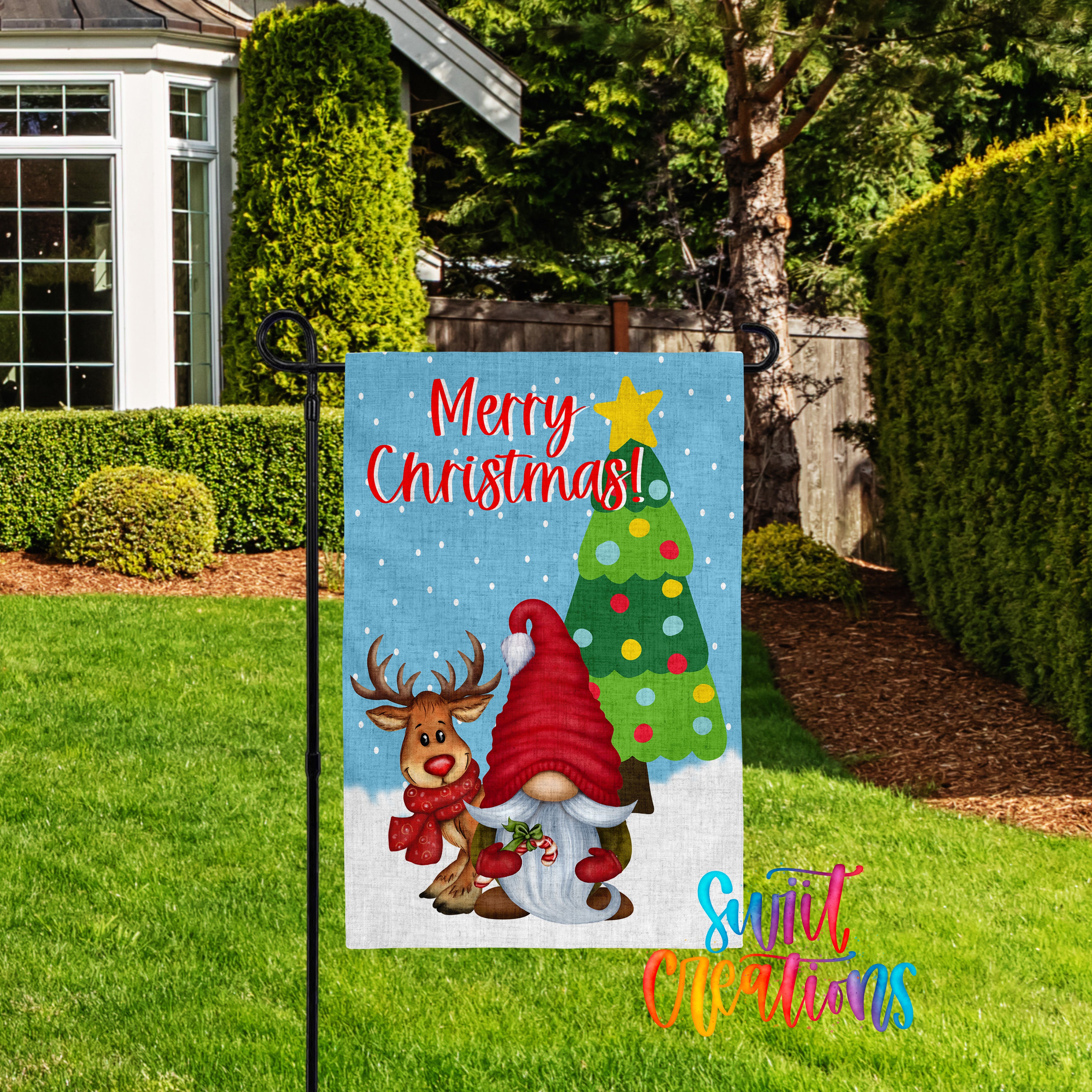 A colorful Christmas-themed garden flag with a gnome and reindeer, set against a snowy background with a Christmas tree.