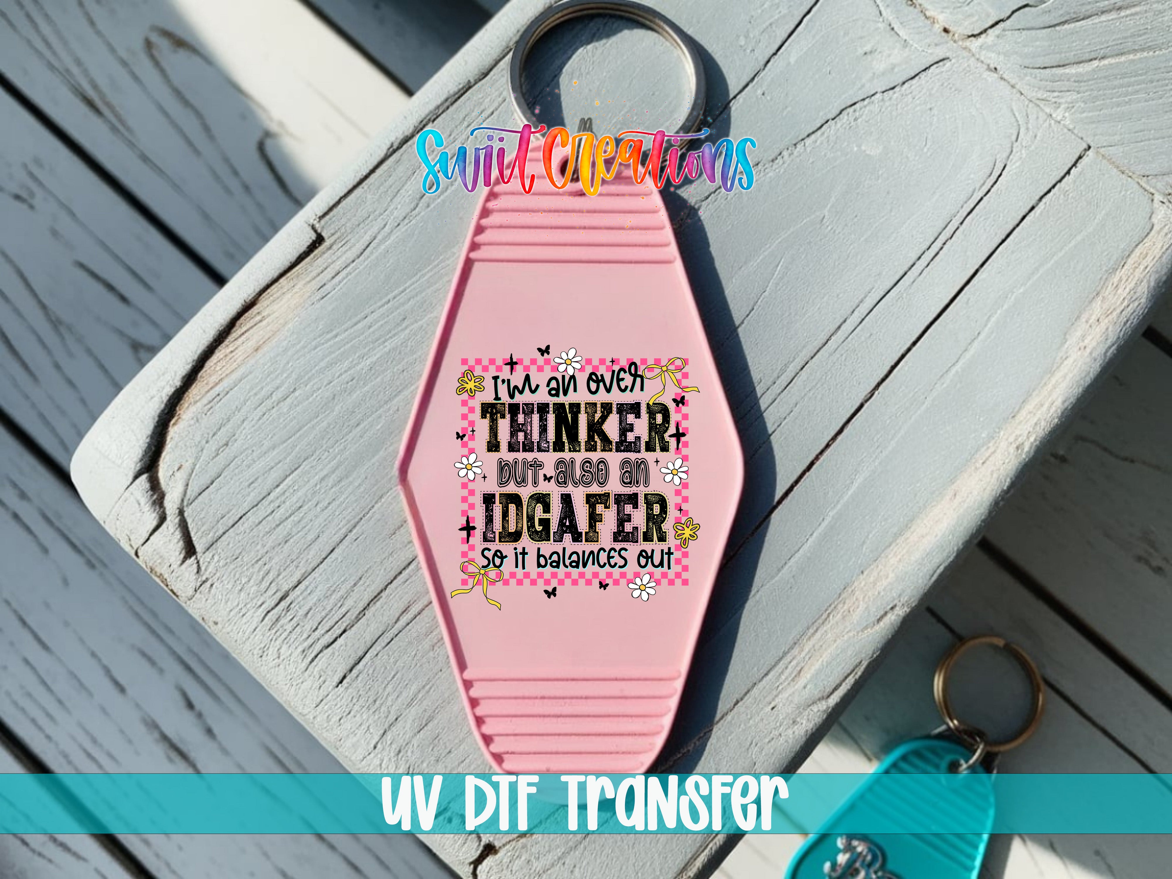 A pink keychain with a humorous text message printed on it, placed on a wooden surface.