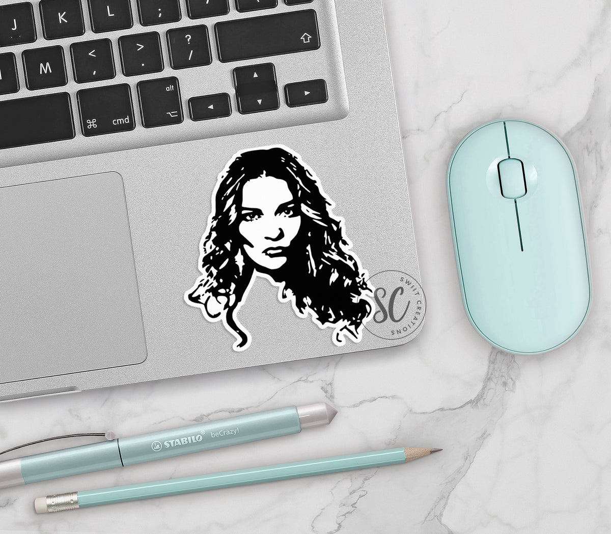 Alexis Portrait vinyl sticker on a silver laptop next to a mint mouse and pens