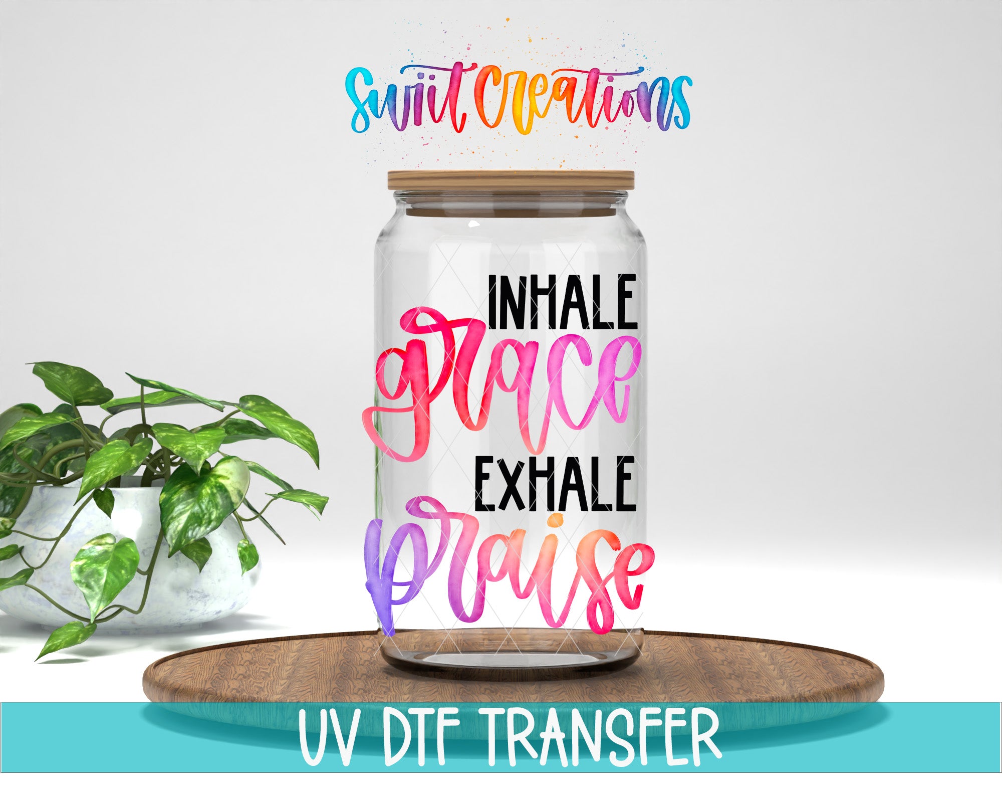 a glass jar with a wooden lid, placed on a wooden surface. The jar has a colorful design with text that reads "Inhale grace, breathe praise". There is also a plant in the background.