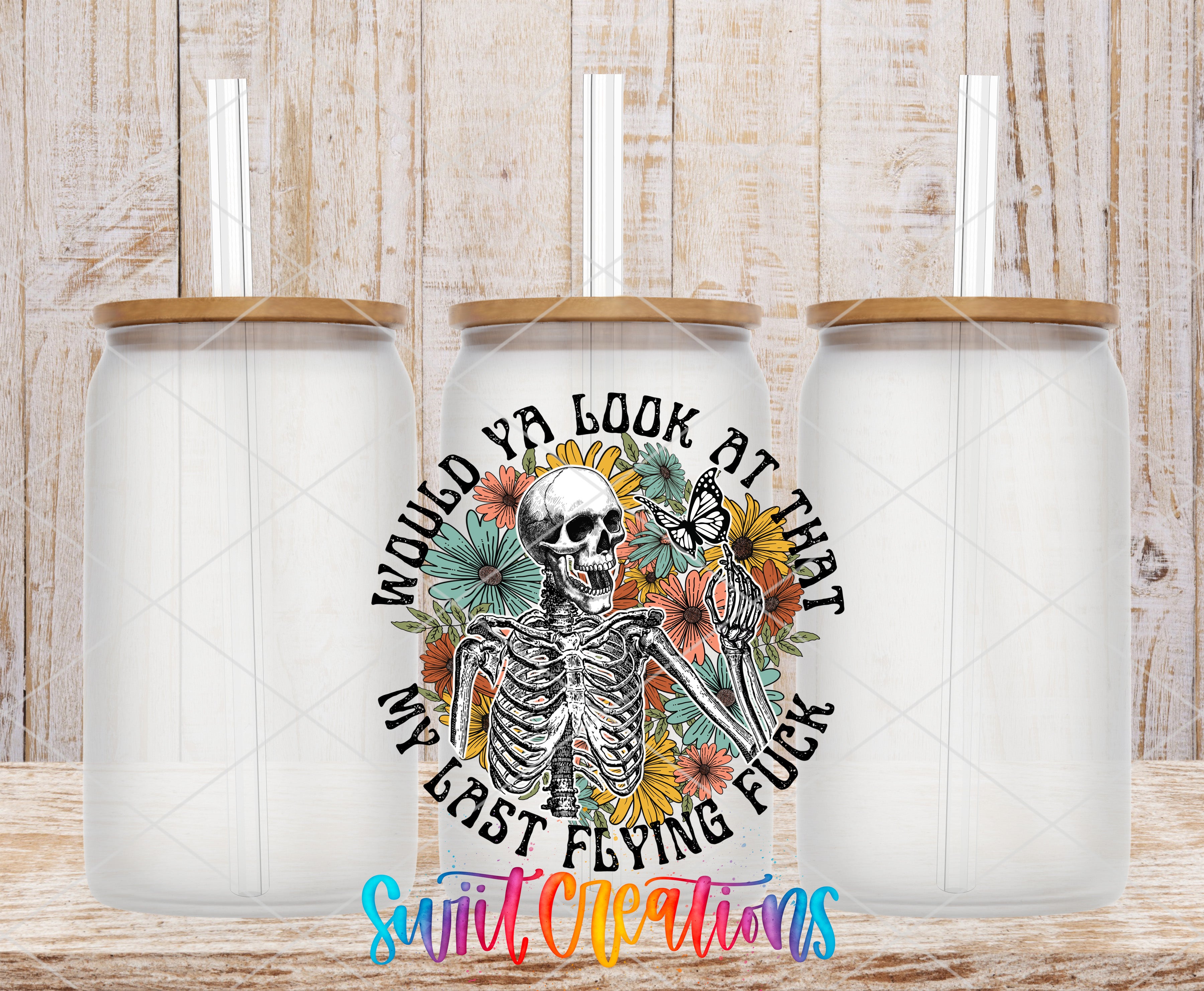 A colorful ceramic mug with a skeleton design and text, placed on a wooden surface.