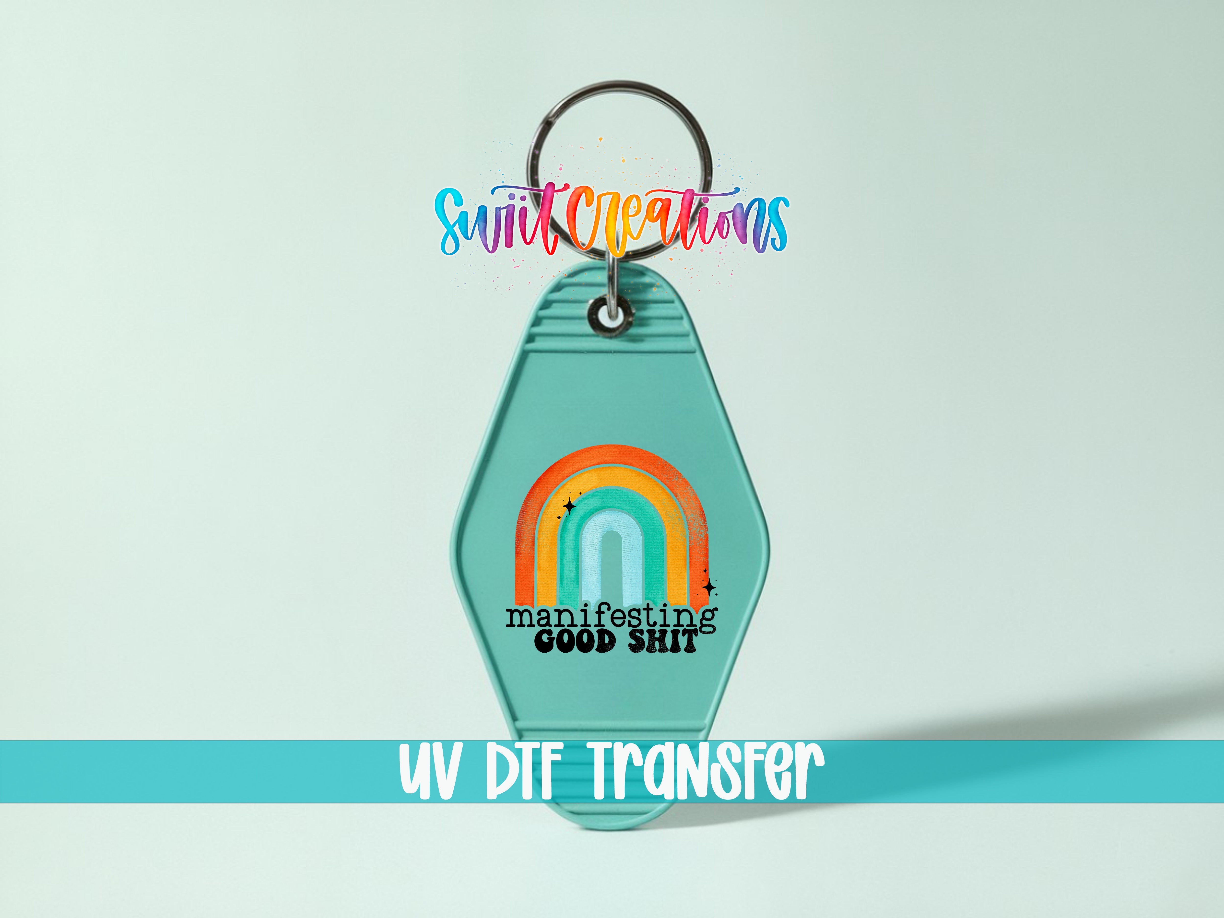 A keychain with a rainbow graphic and the text "manifests good shit" printed on it.