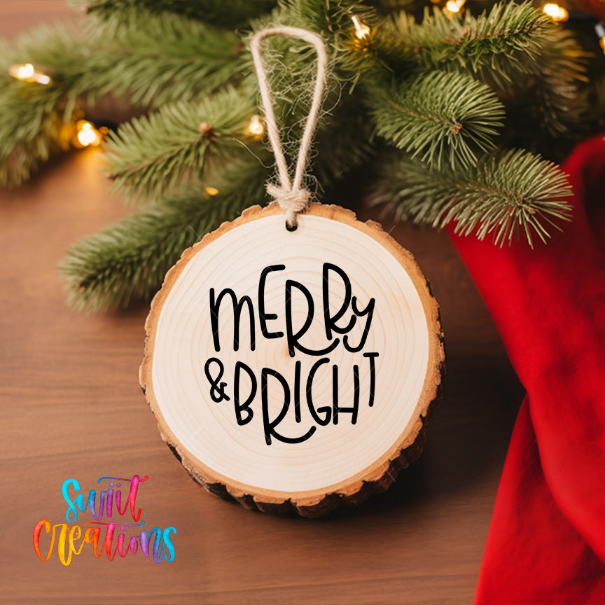 A wooden ornament with the text "merry & bright" hanging from a tree branch, surrounded by pine branches and twinkling lights.