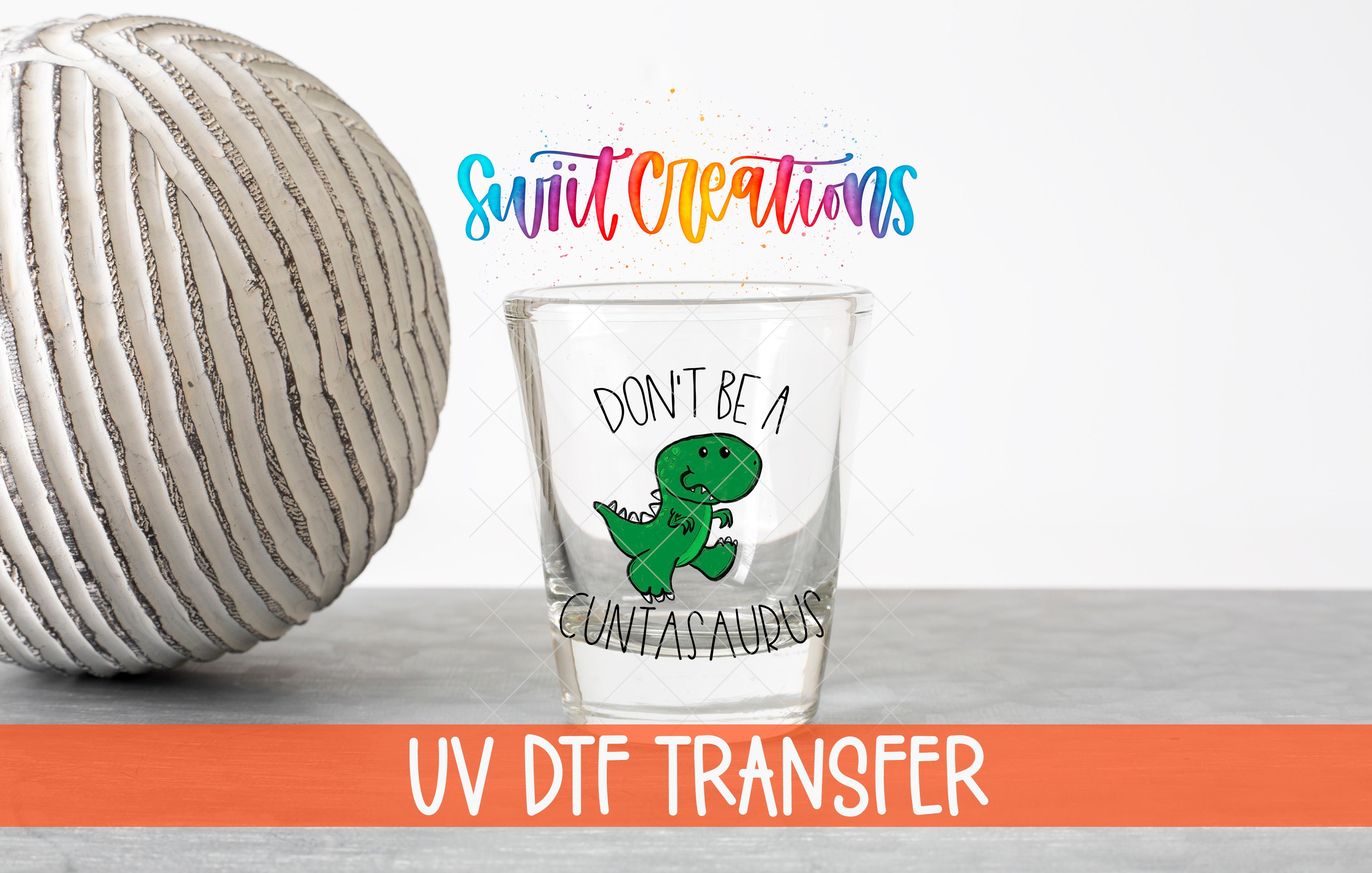 a glass with a dinosaur design and text, along with a ball and a rainbow-colored text overlay.