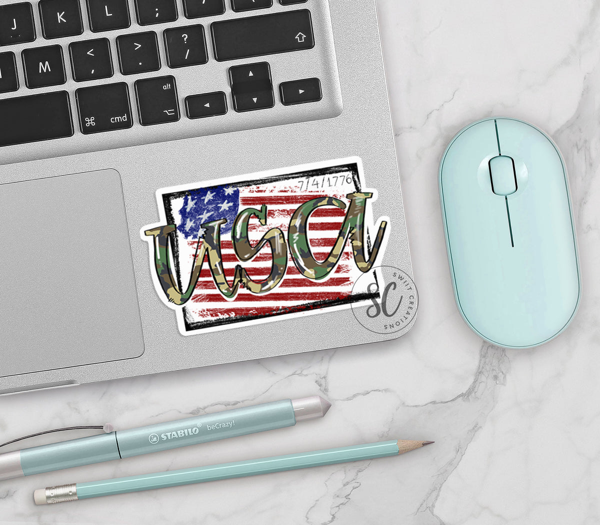 USA Camo vinyl sticker on a silver laptop next to a mint mouse and pens