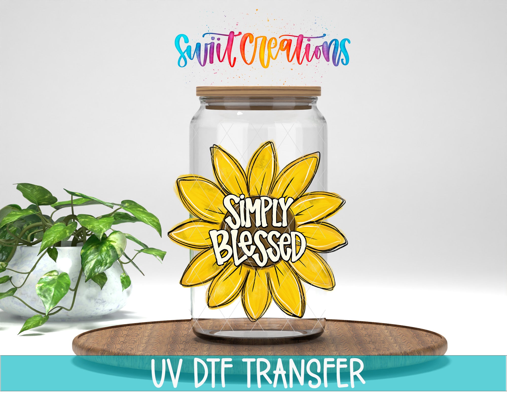 a clear glass jar with a yellow flower design and the text "Simply Blessed" on it, placed on a wooden surface. There is also a potted plant in the background.