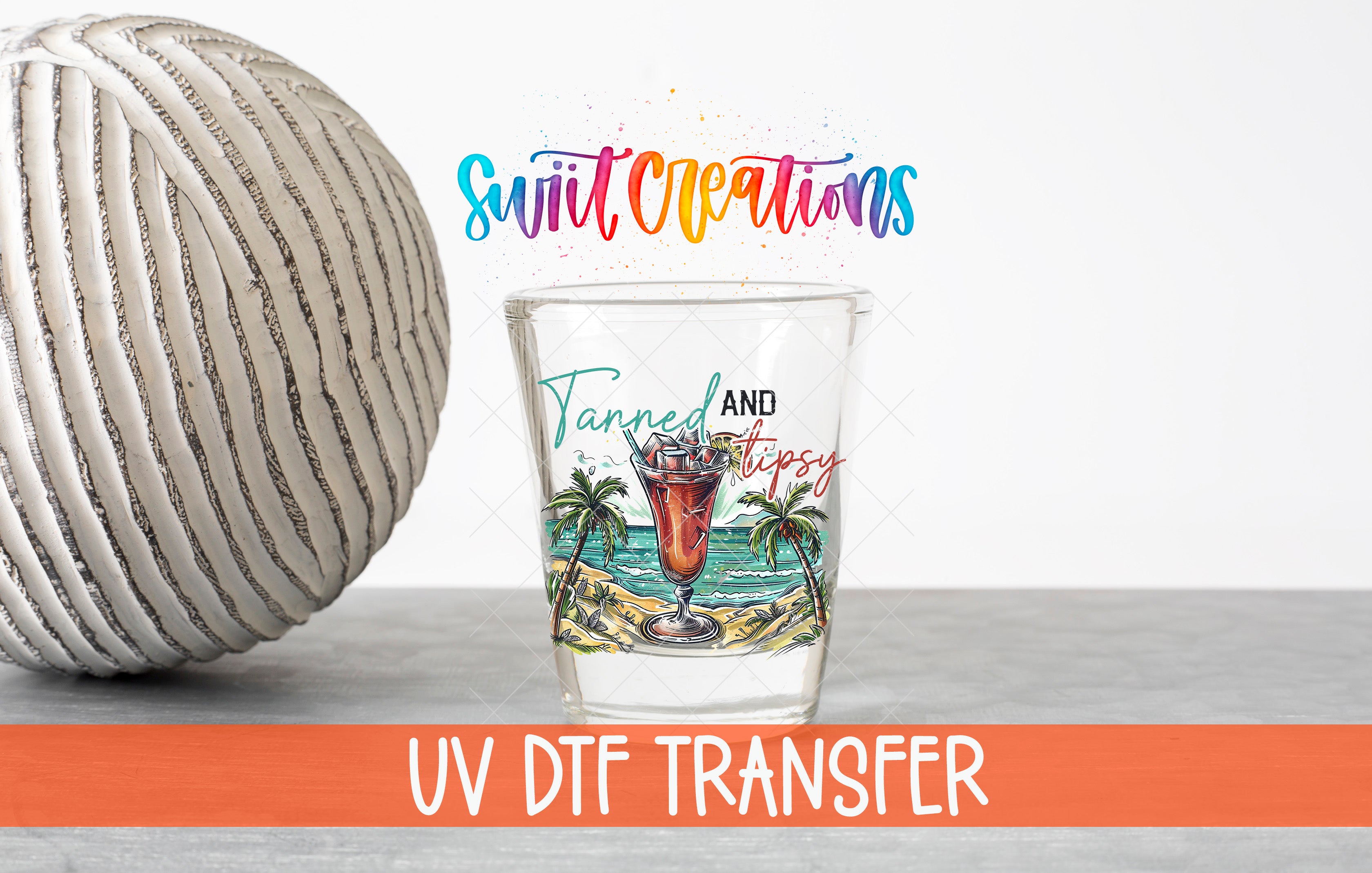 a shot glass with a tropical beach scene and palm trees, along with a text overlay that says "Swift Creations Tanned and Tipsy" and "UV Dtf Transfer".