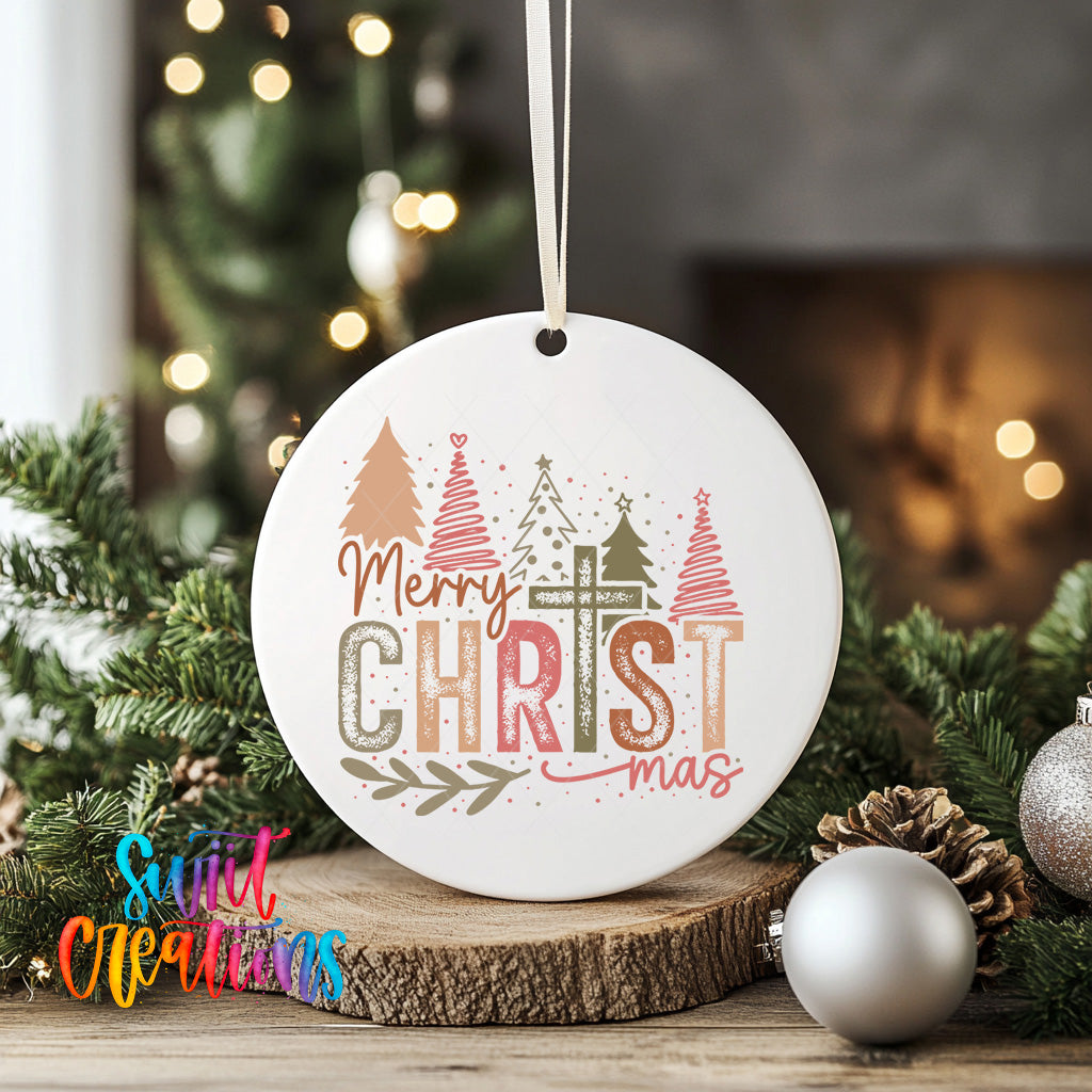 A white ceramic ornament with the text "Merry Christmas" and Christmas trees is displayed on a wooden surface, surrounded by holiday decorations such as ornaments and pine cones.