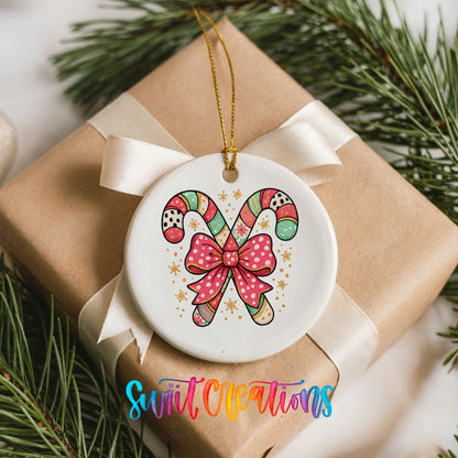 A white ceramic ornament with a bow and colorful candy canes is displayed on a brown gift box, surrounded by pine branches.