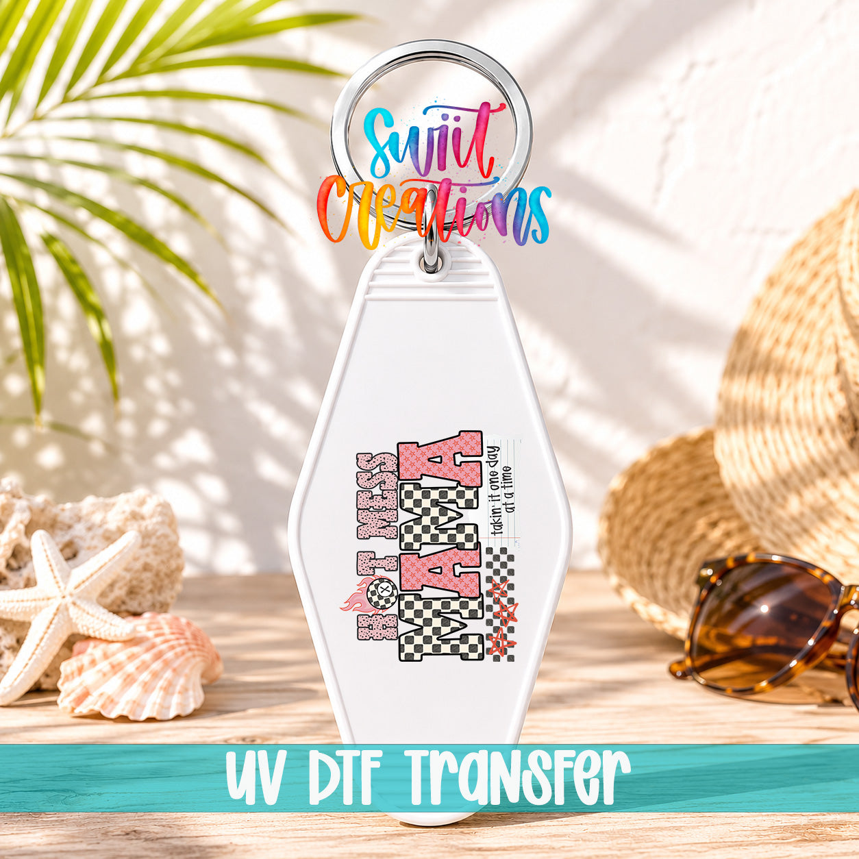 A keychain with a colorful design and text, placed on a wooden surface with sunglasses and a straw hat in the background.