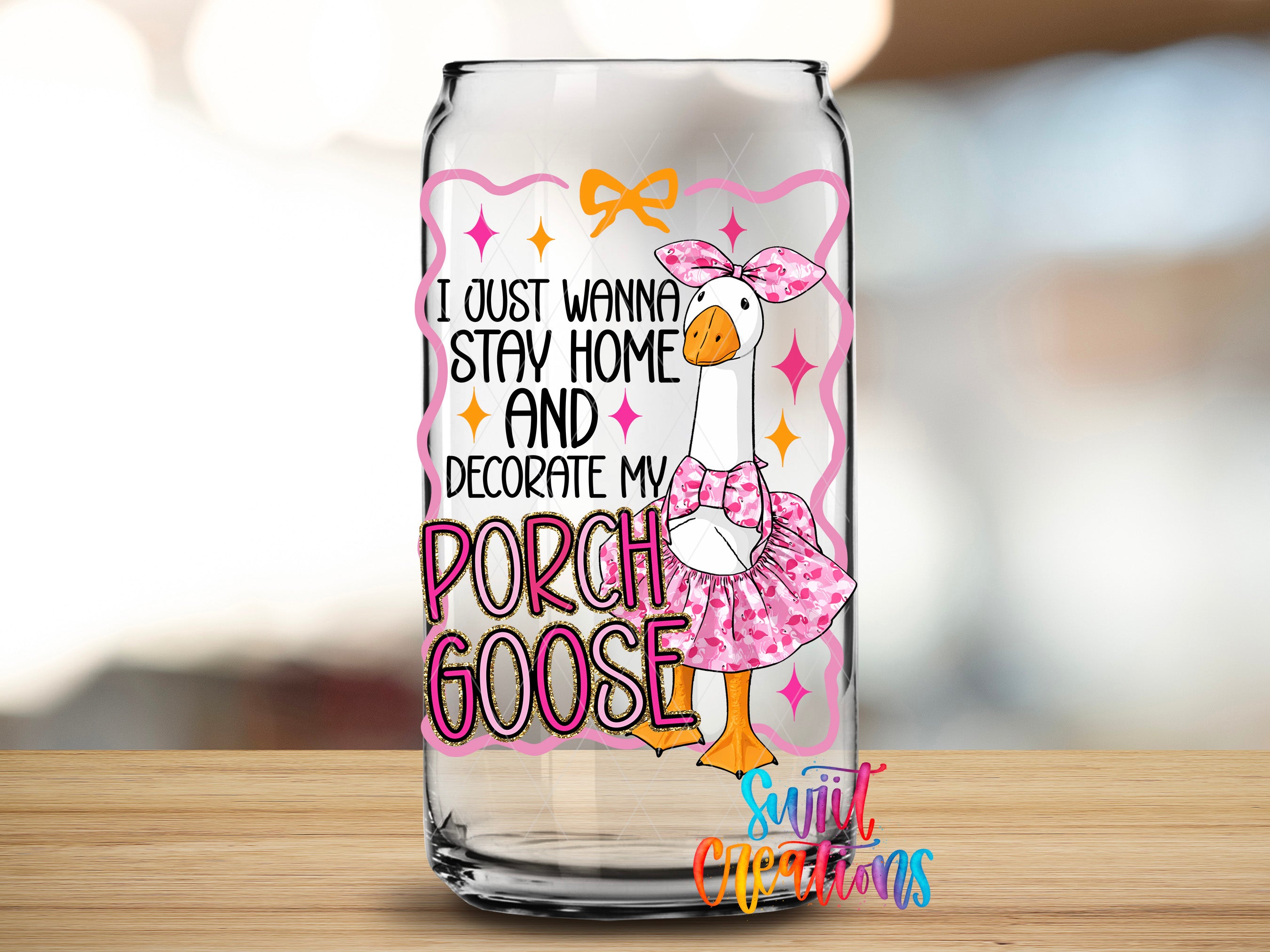 A glass can with a cartoon image of a goose wearing a pink dress and bow, along with text that says "I just wanna stay home and decorate my porch goose".
