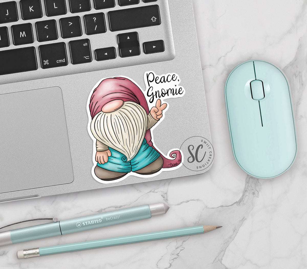 Peace Gnomie vinyl sticker on a silver laptop next to a mint mouse and pens