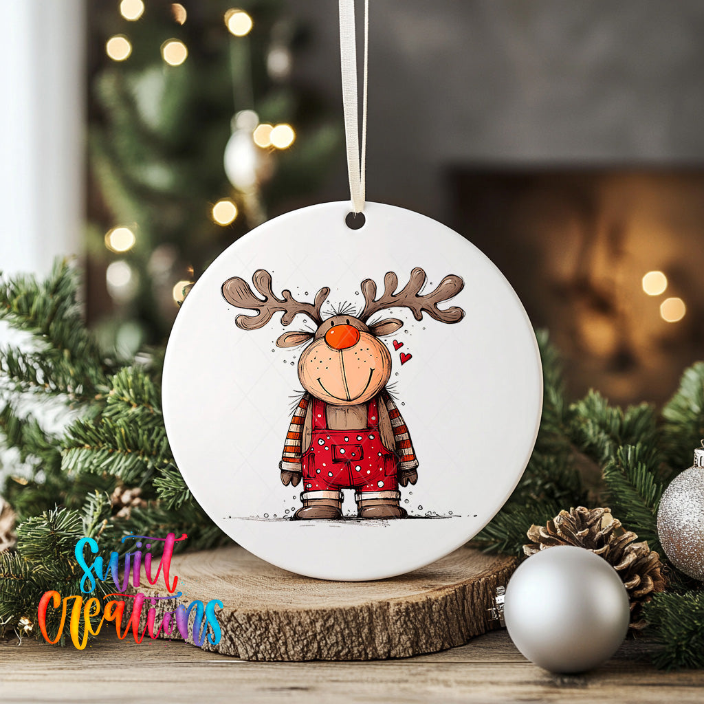 A white ornament featuring a cartoon reindeer with antlers and a red sweater, surrounded by Christmas decorations and greenery.