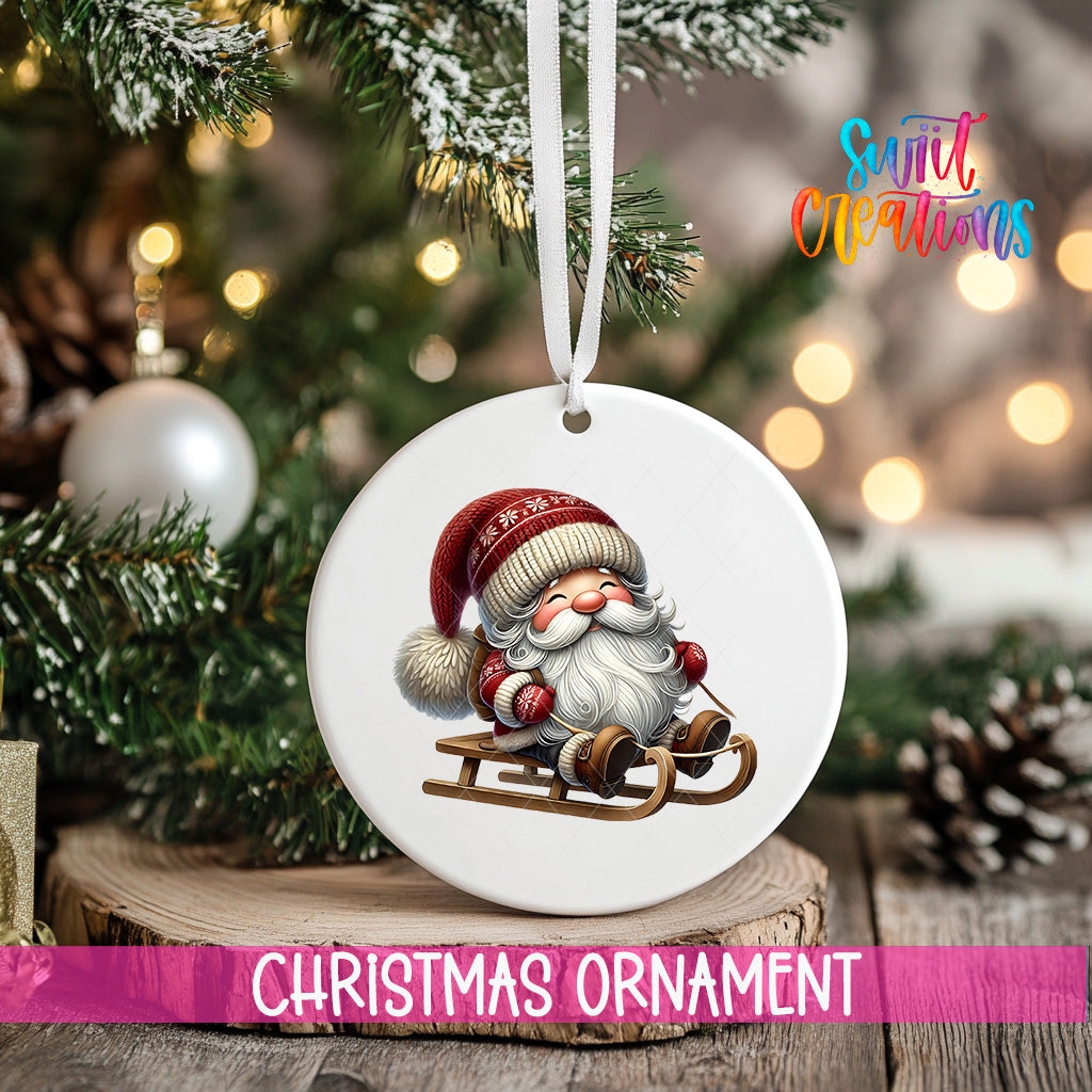 A white Christmas ornament featuring a smiling Santa Claus on a sled, hanging on a tree branch with a ribbon.