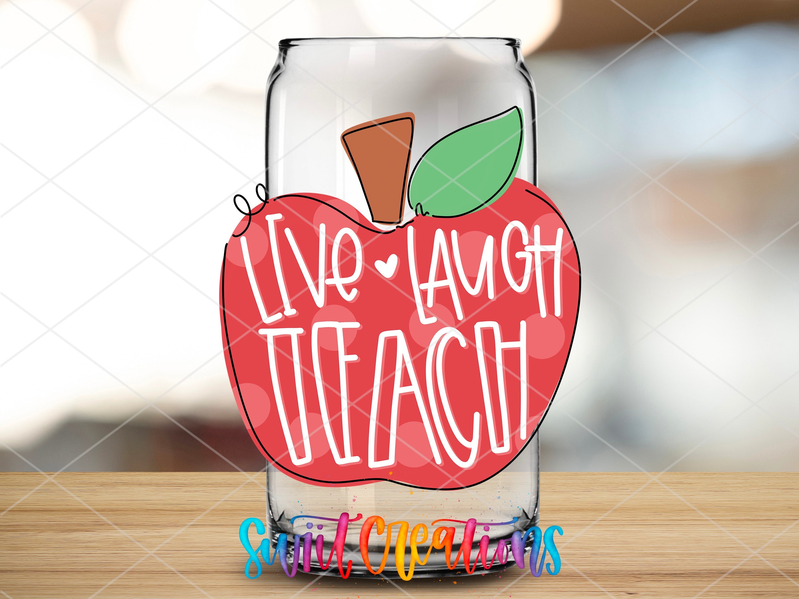 a glass with an apple on it that says live laugh teach