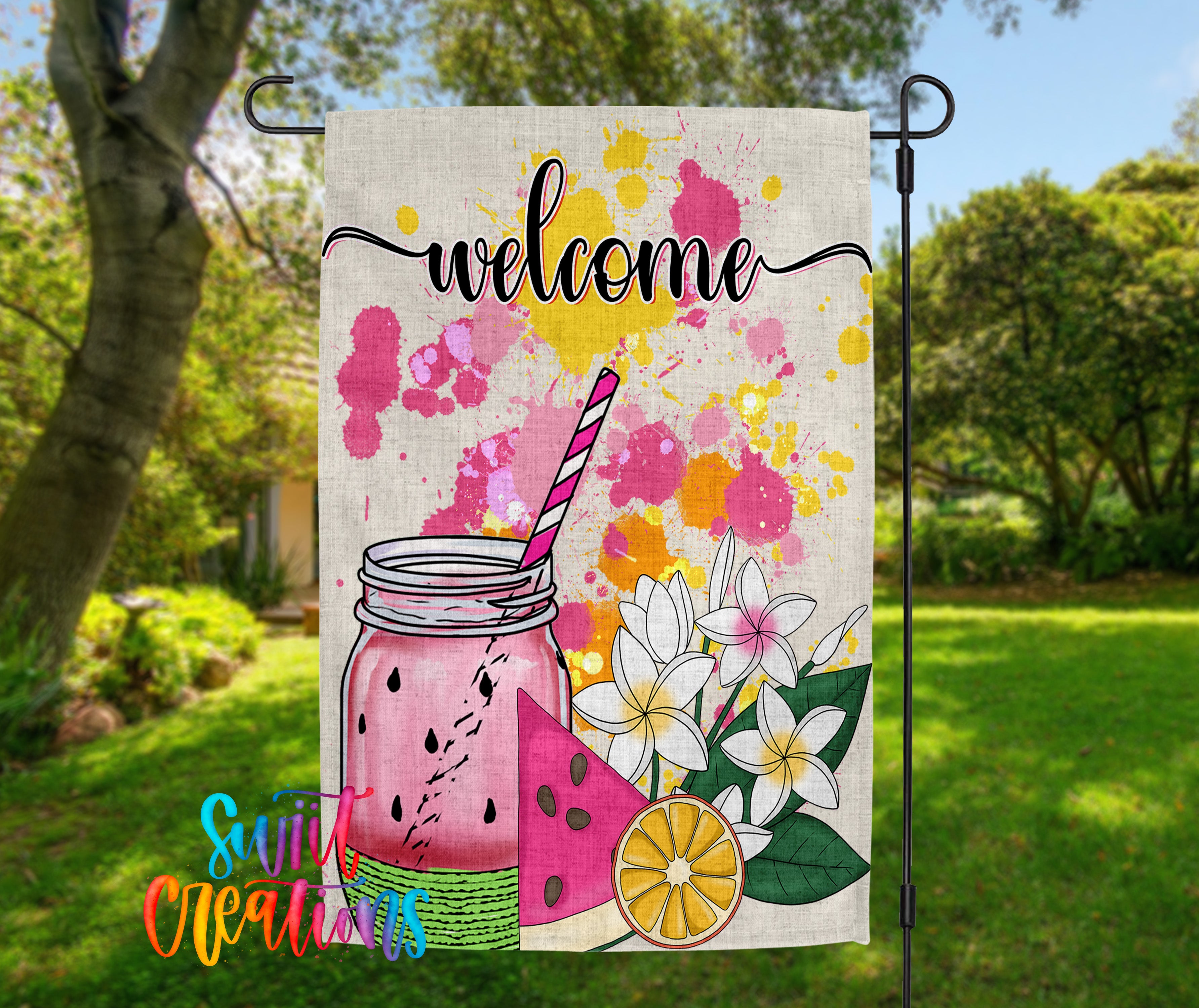 A colorful welcome sign with a mason jar, watermelon, and flowers, set against a backdrop of trees and greenery.
