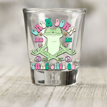 Calm Down And Let That Sh*t Go shot glass UV DTF transfer with meditating frog with flowers and peace signs on a clear shot glass