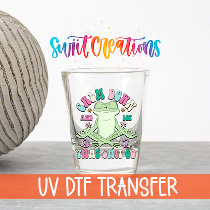 Calm Down And Let That Sh*t Go UV DTF transfer on a clear shot glass with the Swiit Creations logo and UV DTF Transfer banner