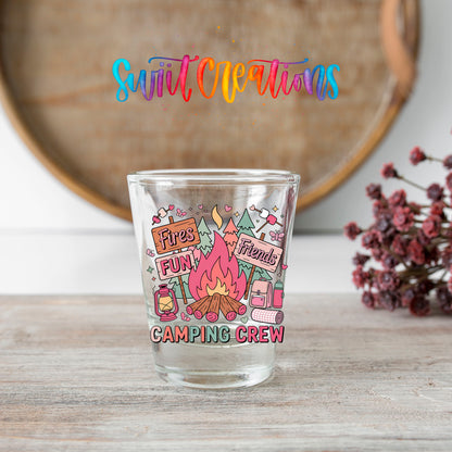 Camping Crew shot glass transfer on a clear glass beside a wooden barrel and dried flowers