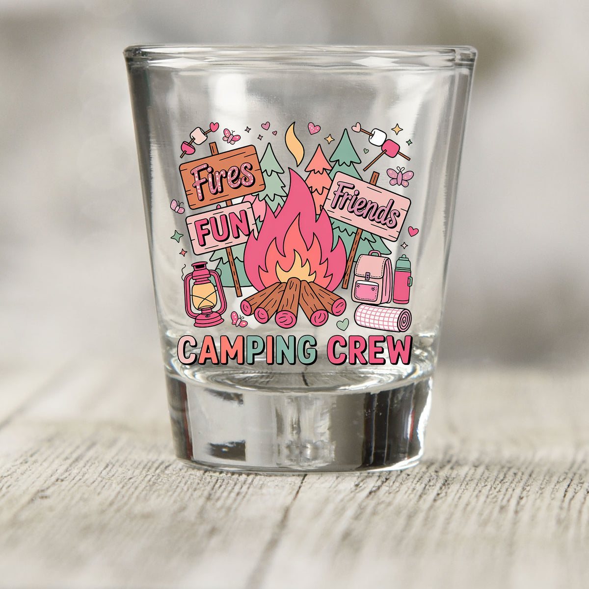 Camping Crew shot glass UV DTF transfer with campfire, signs, trees, and camping gear details on a clear shot glass
