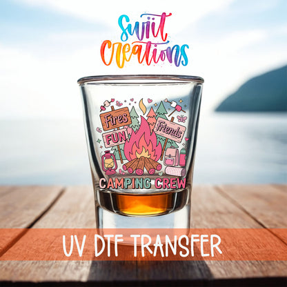 Camping Crew shot glass UV DTF transfer on a filled shot glass on a dock by the water